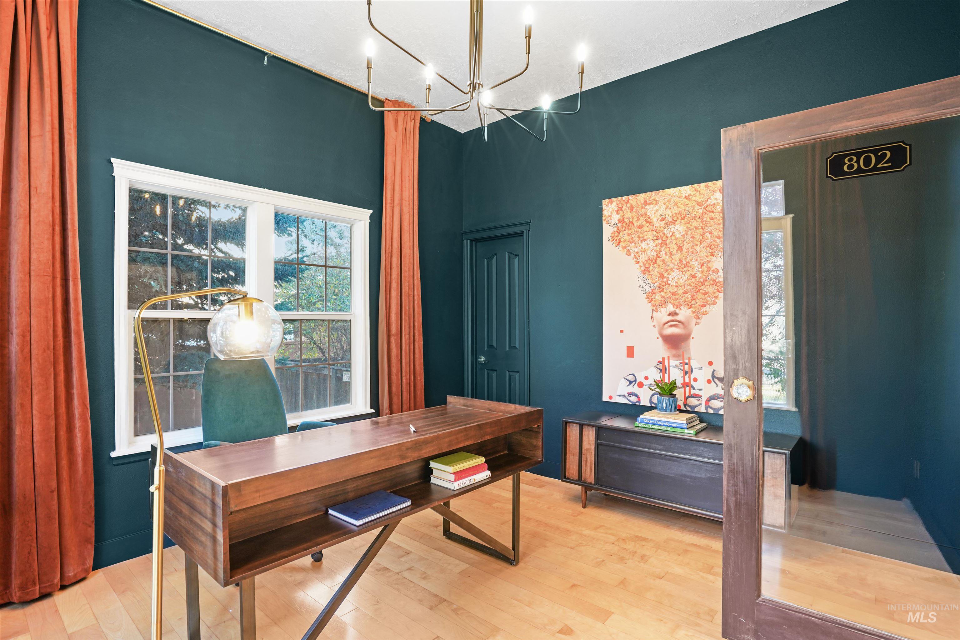 Office space with light wood-type flooring, healthy amount of natural light, and a chandelier