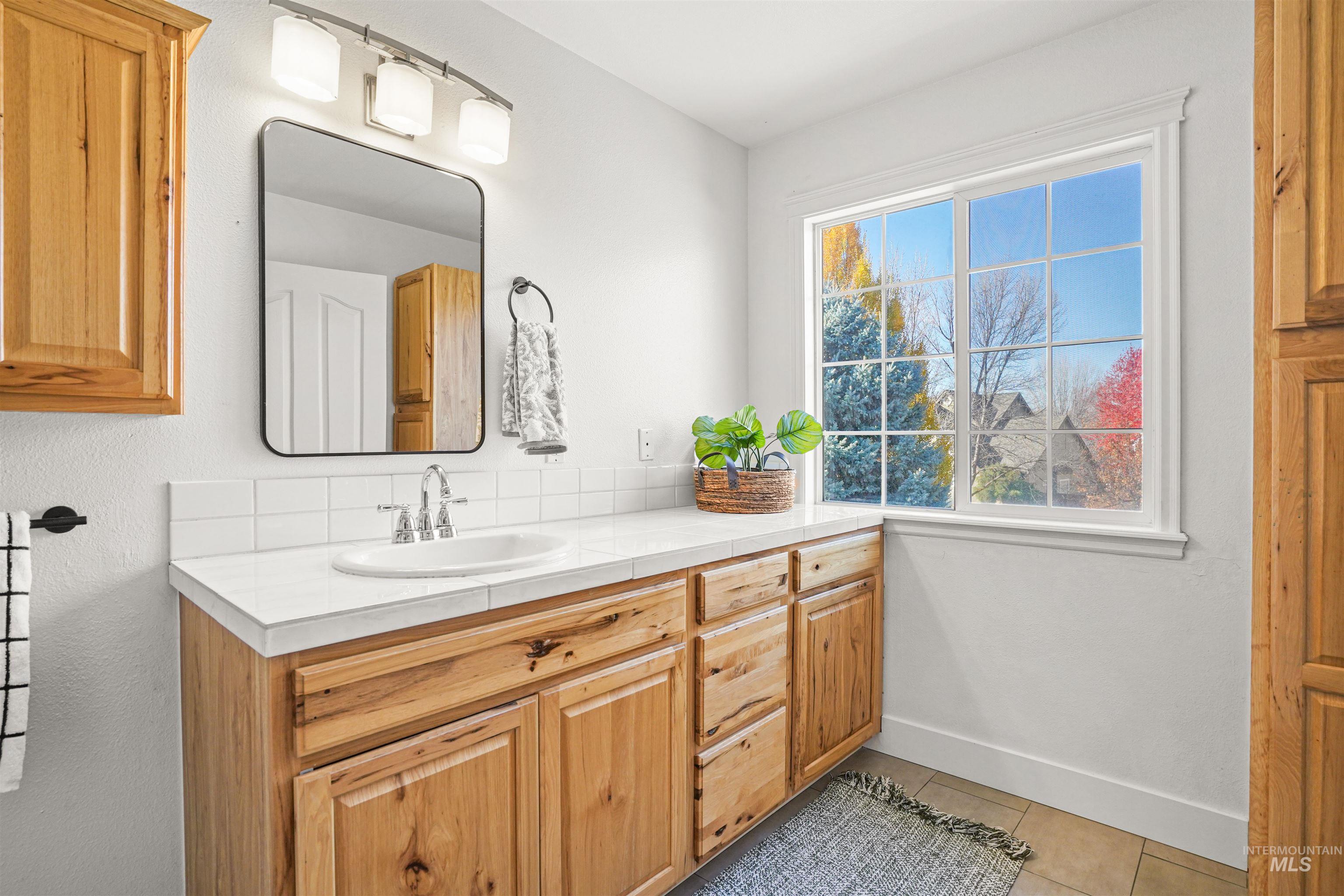 Bathroom featuring vanity, light tile patterned flooring, and backsplash