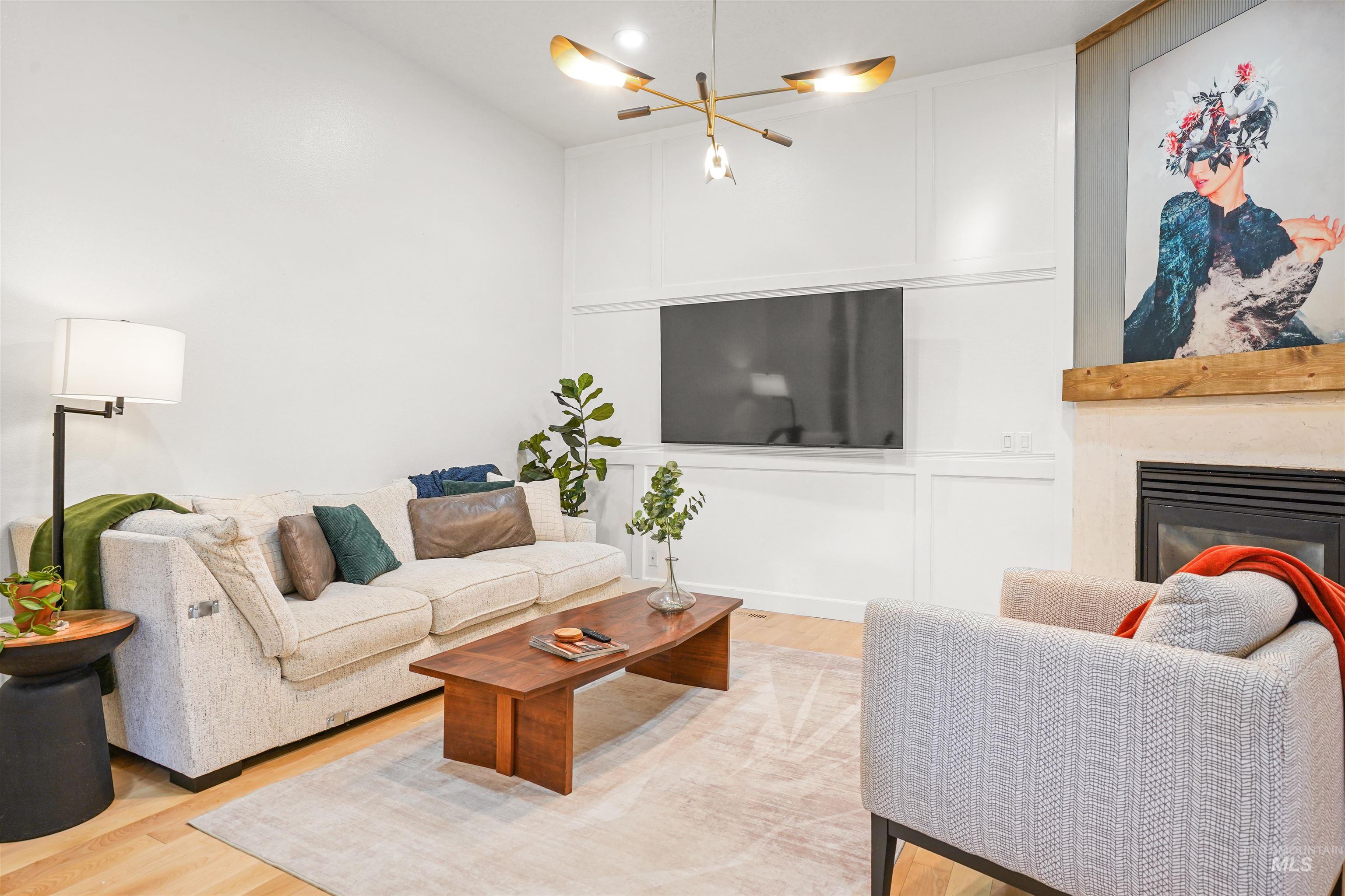 Living area featuring light wood-style flooring, a glass covered fireplace, and a chandelier