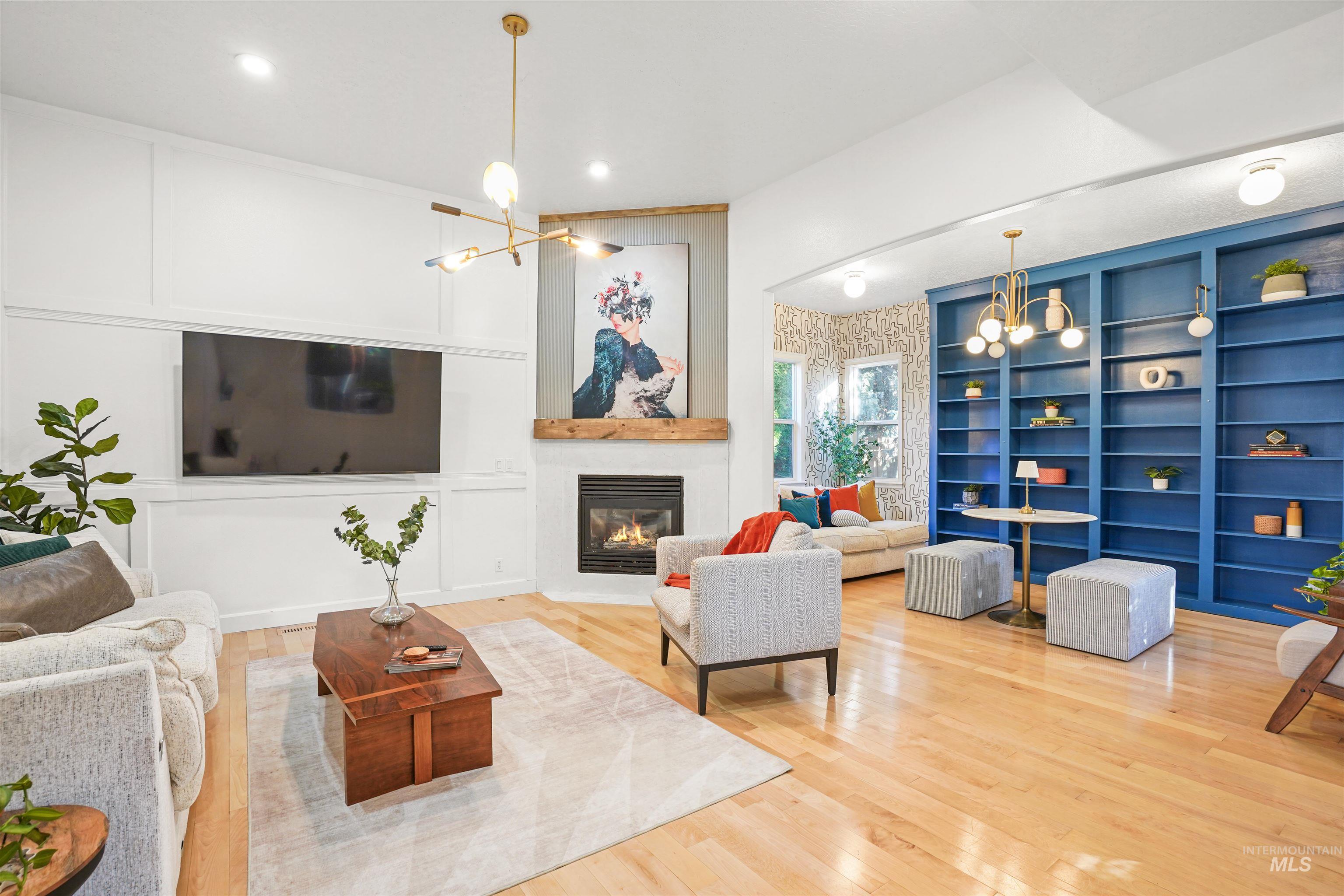 Living room featuring a chandelier, built in shelves, a glass covered fireplace, wood finished floors, and recessed lighting