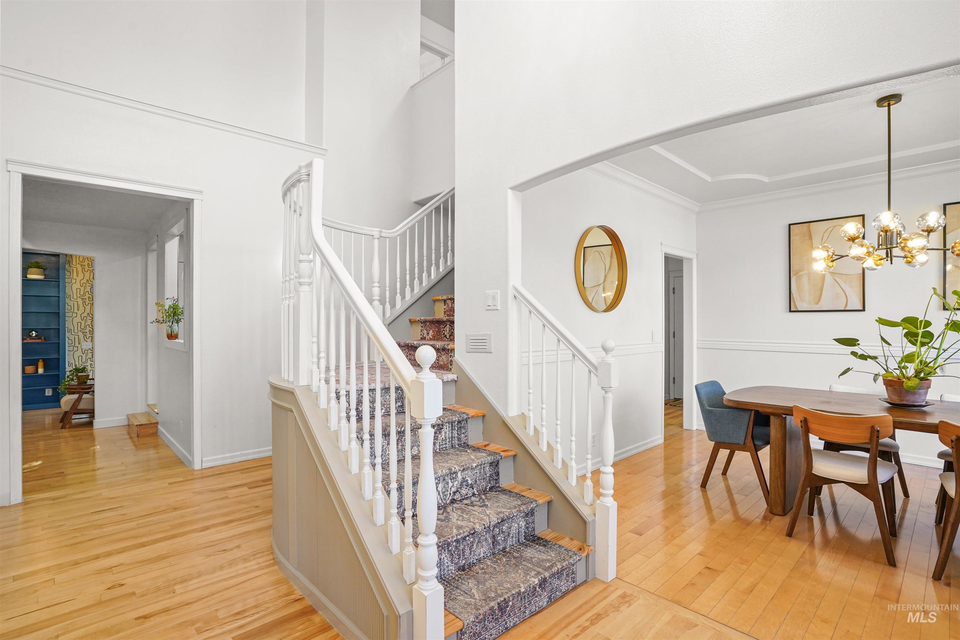 Stairs featuring hardwood / wood-style flooring, a chandelier, and a towering ceiling