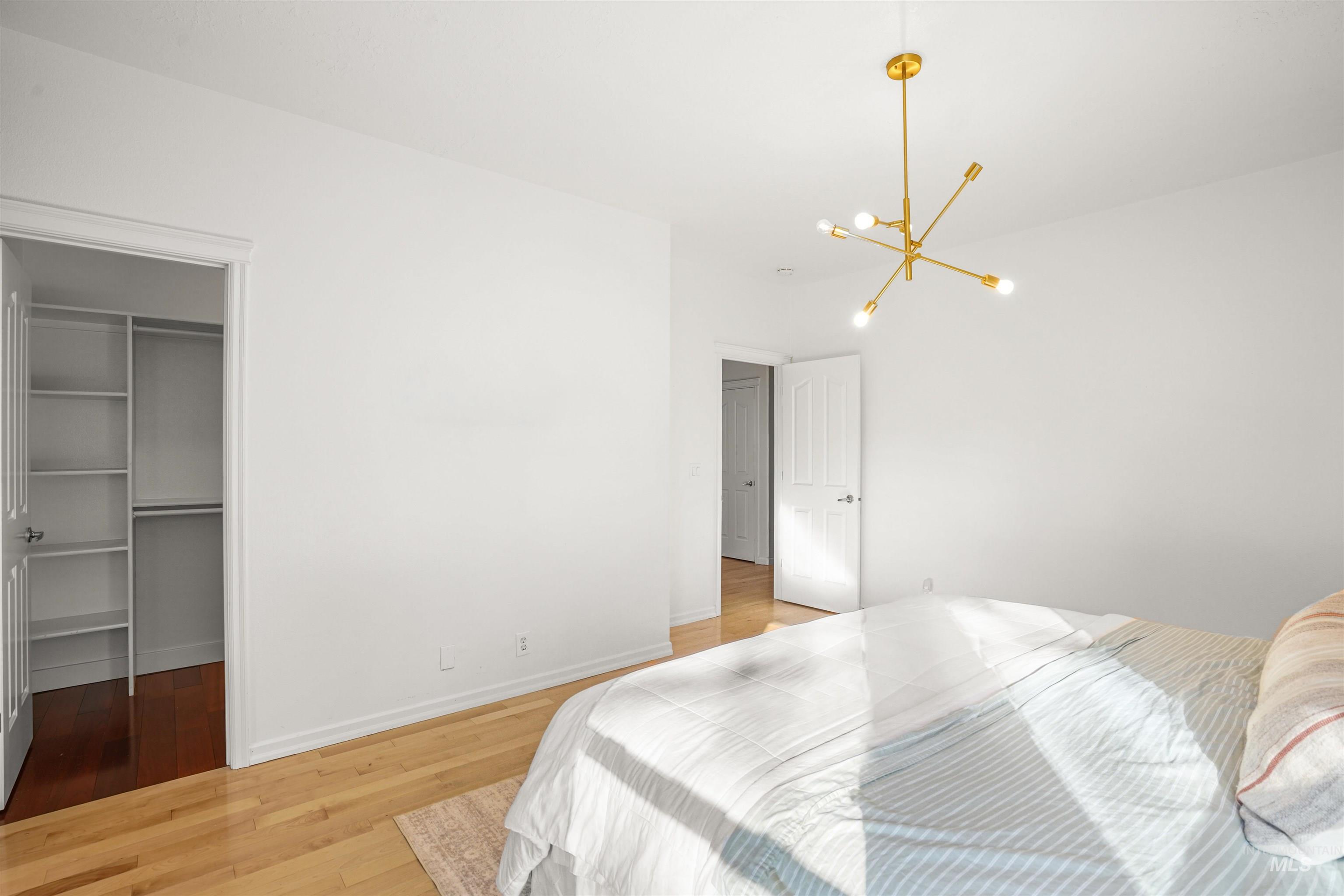 Bedroom with a spacious closet, light wood finished floors, and a chandelier