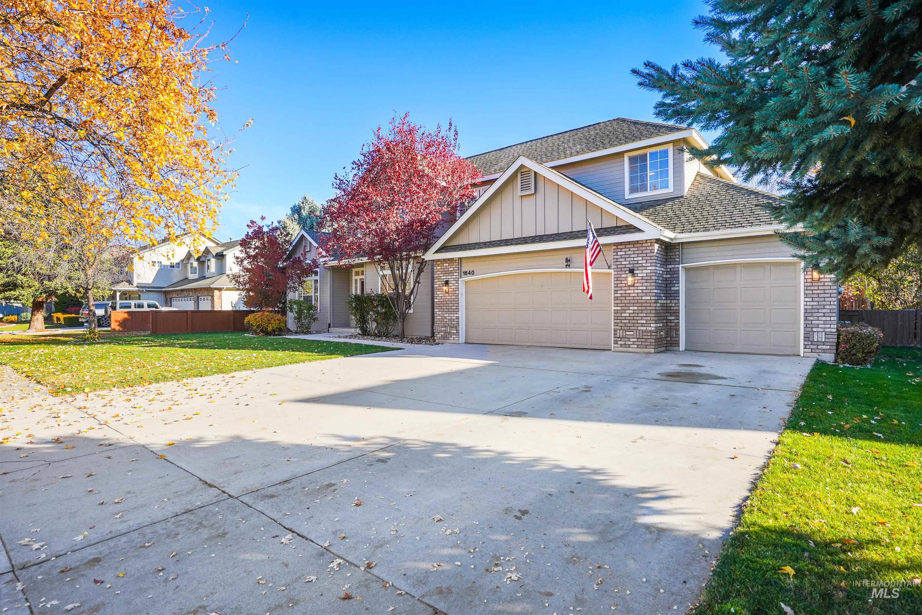 Traditional-style home with board and batten siding, driveway, a shingled roof, a garage, and brick siding
