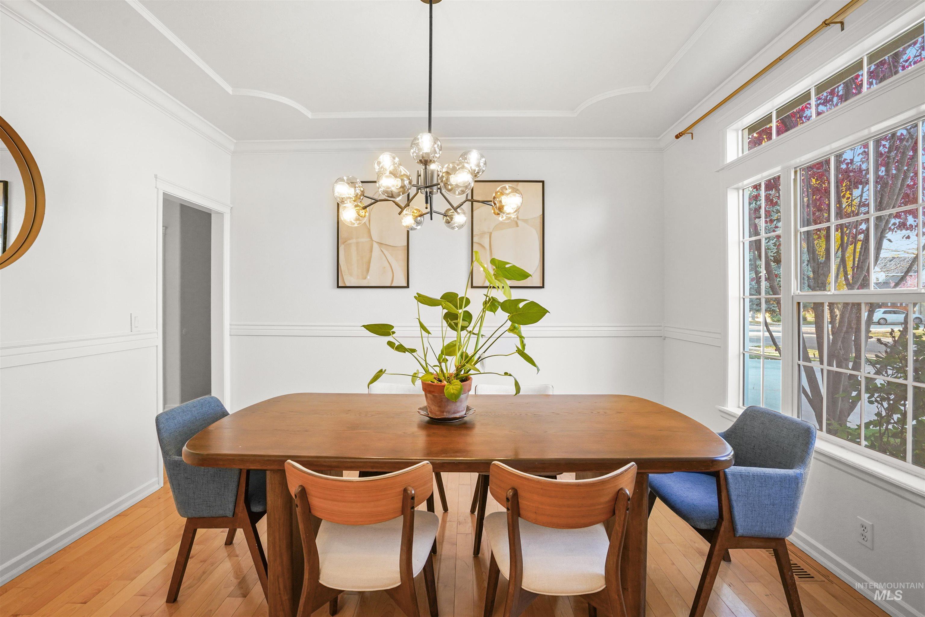Dining area with hardwood / wood-style flooring, a chandelier, and ornamental molding