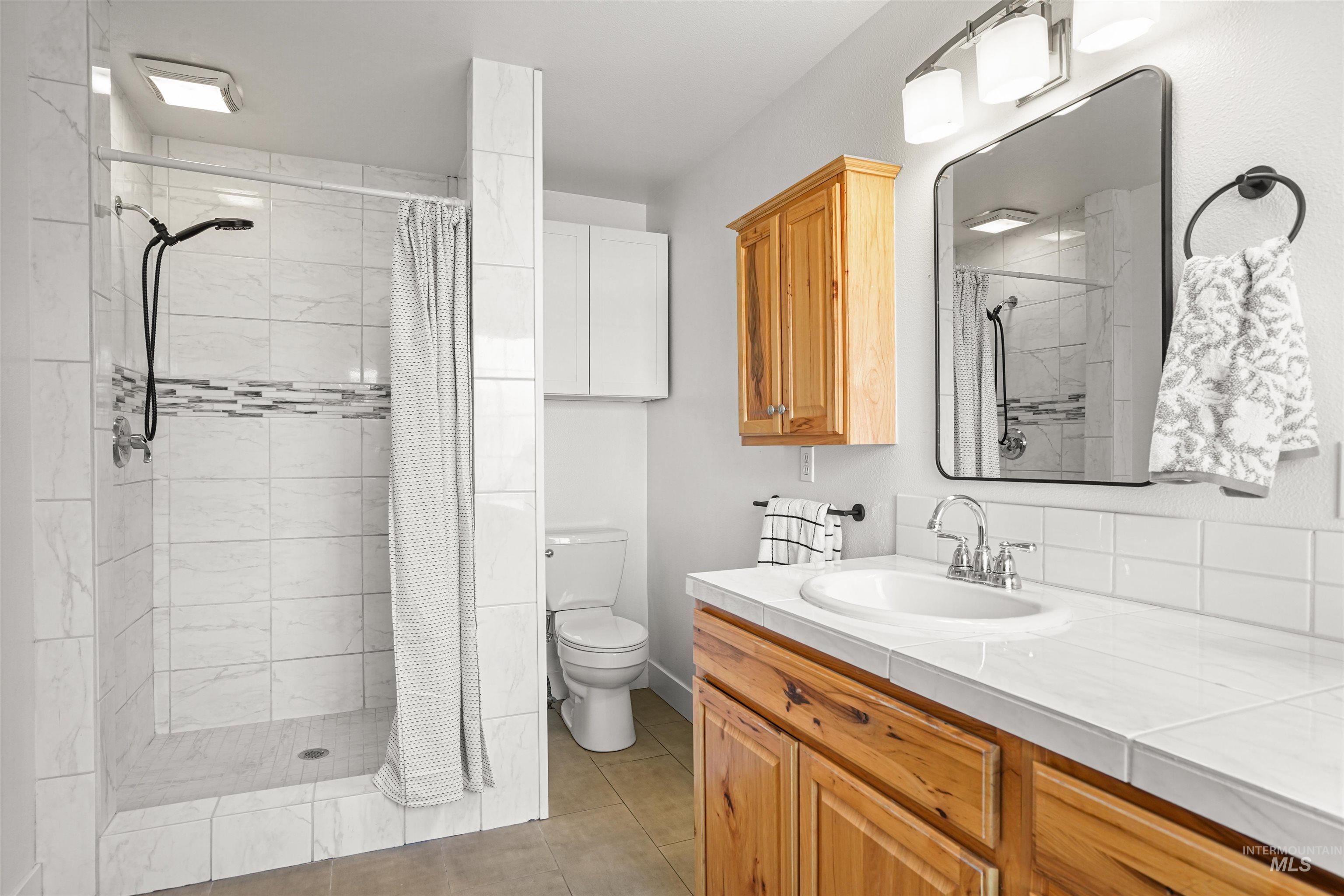 Full bath with a stall shower, vanity, and light tile patterned floors