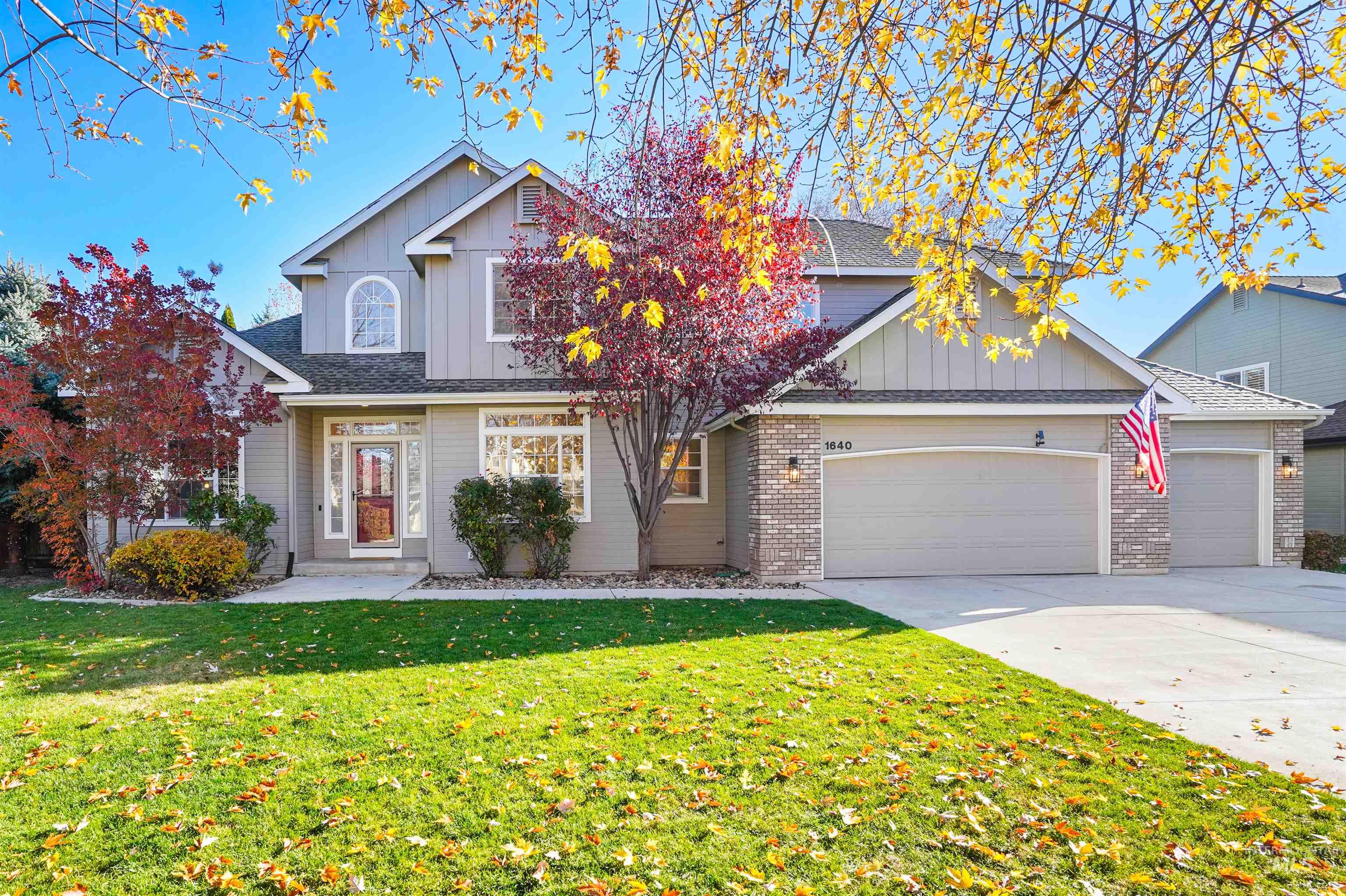 Traditional home with board and batten siding, driveway, a front yard, a garage, and roof with shingles
