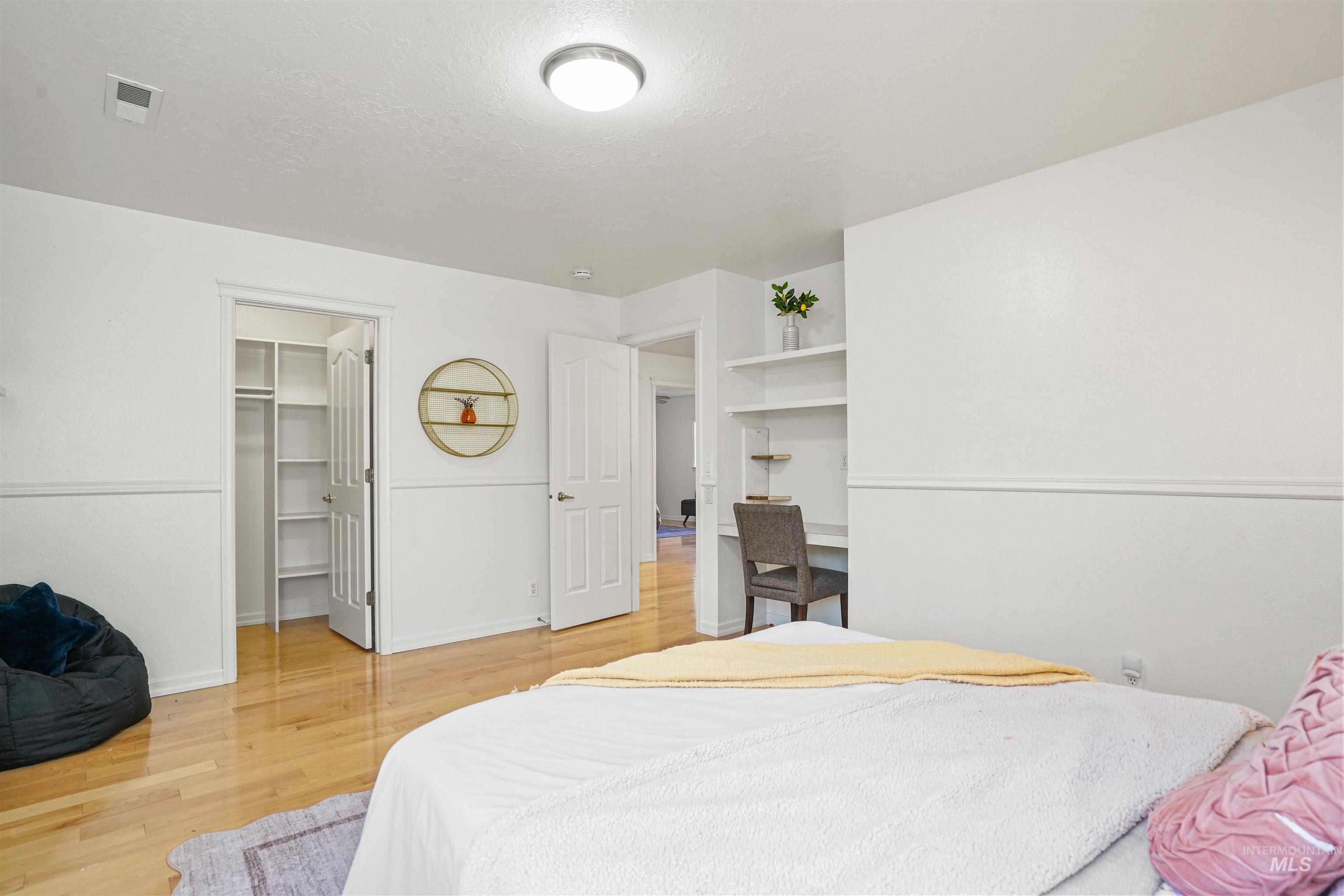 Bedroom featuring light wood-style flooring, a walk in closet, and a textured ceiling