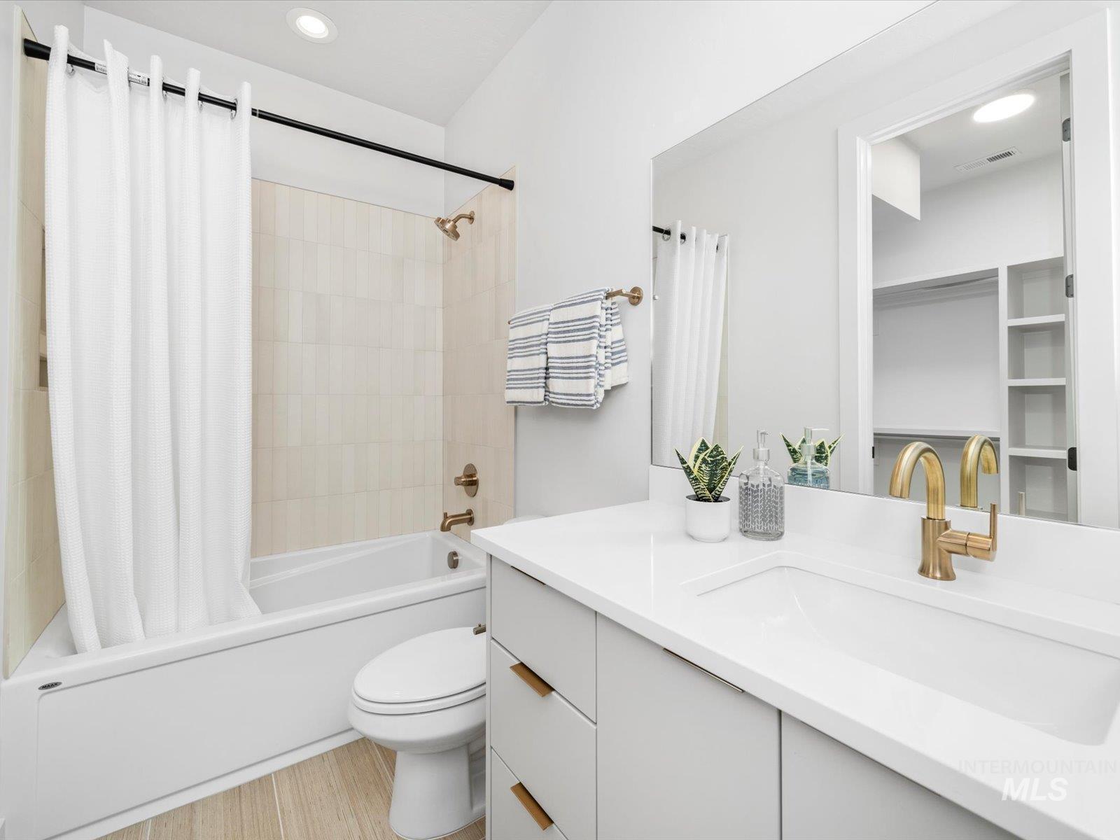 Bathroom featuring shower / bath combination with curtain, vanity, and recessed lighting