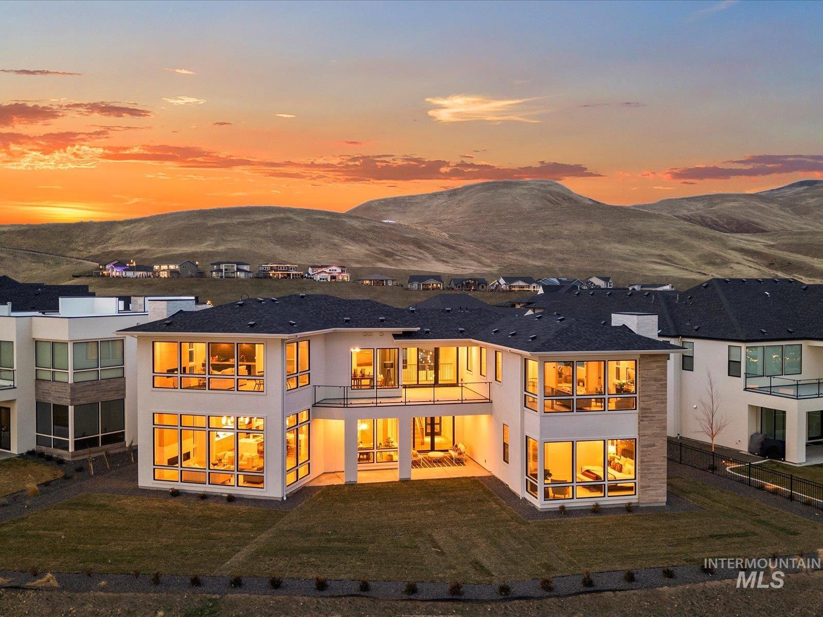 Back of house featuring stucco siding, a lawn, a mountain view, and a patio