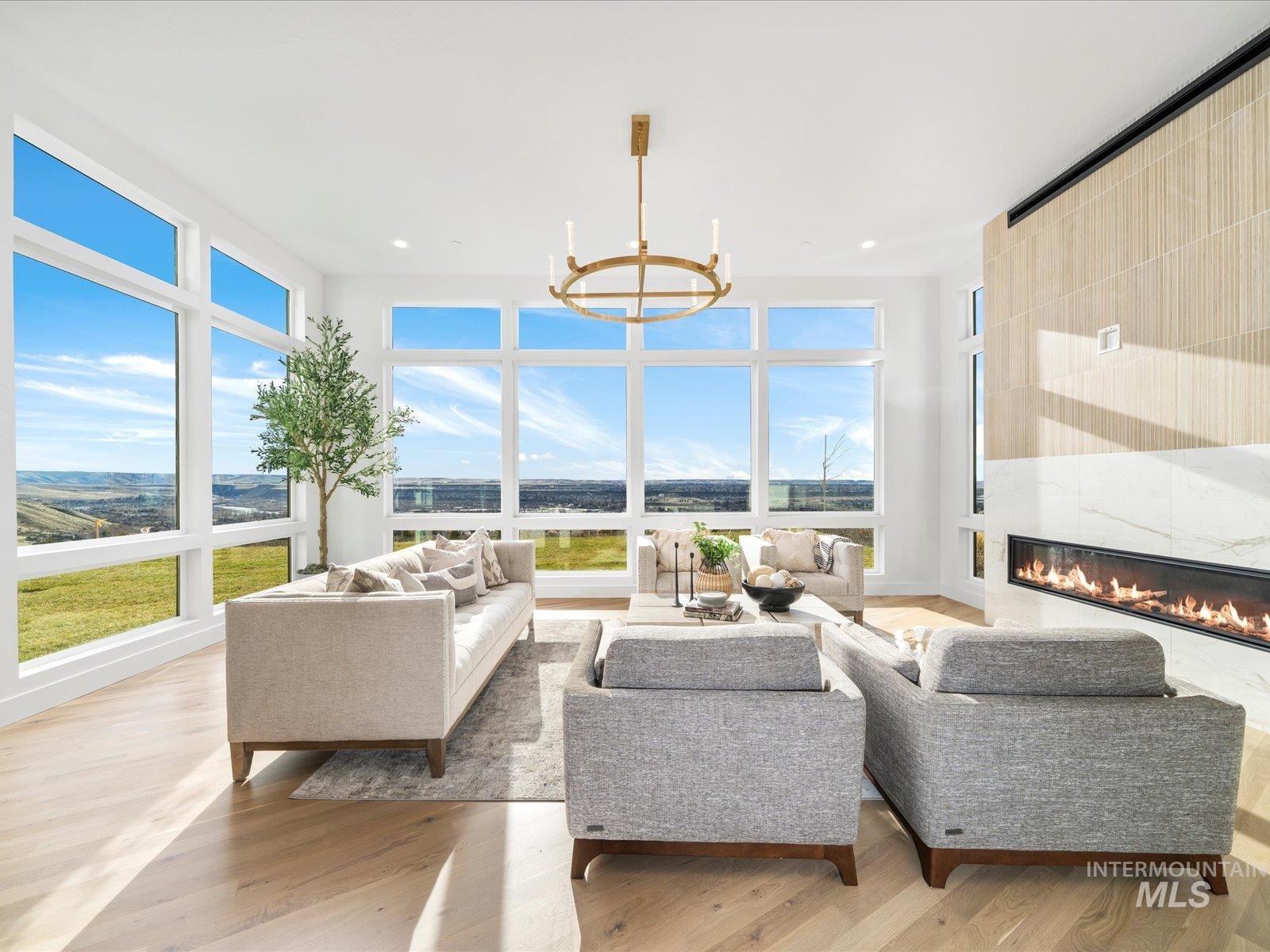 Living area with light wood-type flooring, a fireplace, a chandelier, and healthy amount of natural light