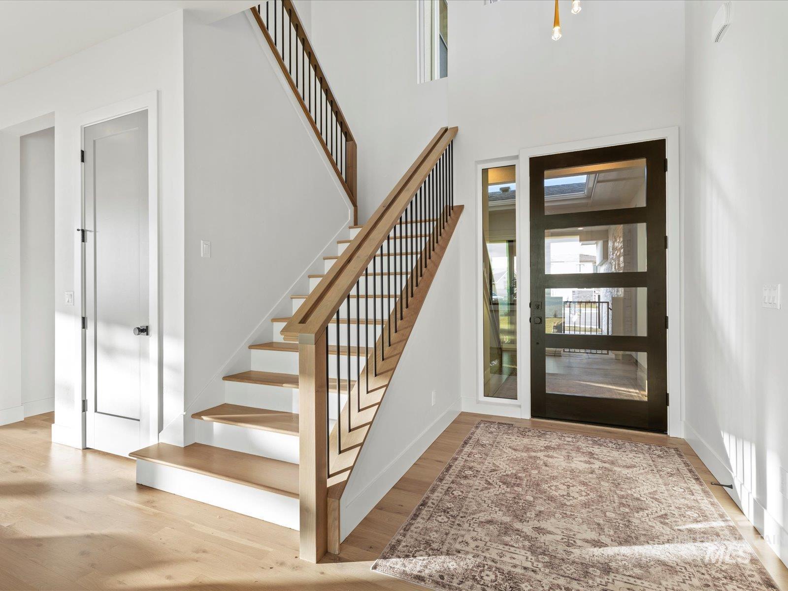 Entryway with stairs, light wood-type flooring, and a high ceiling