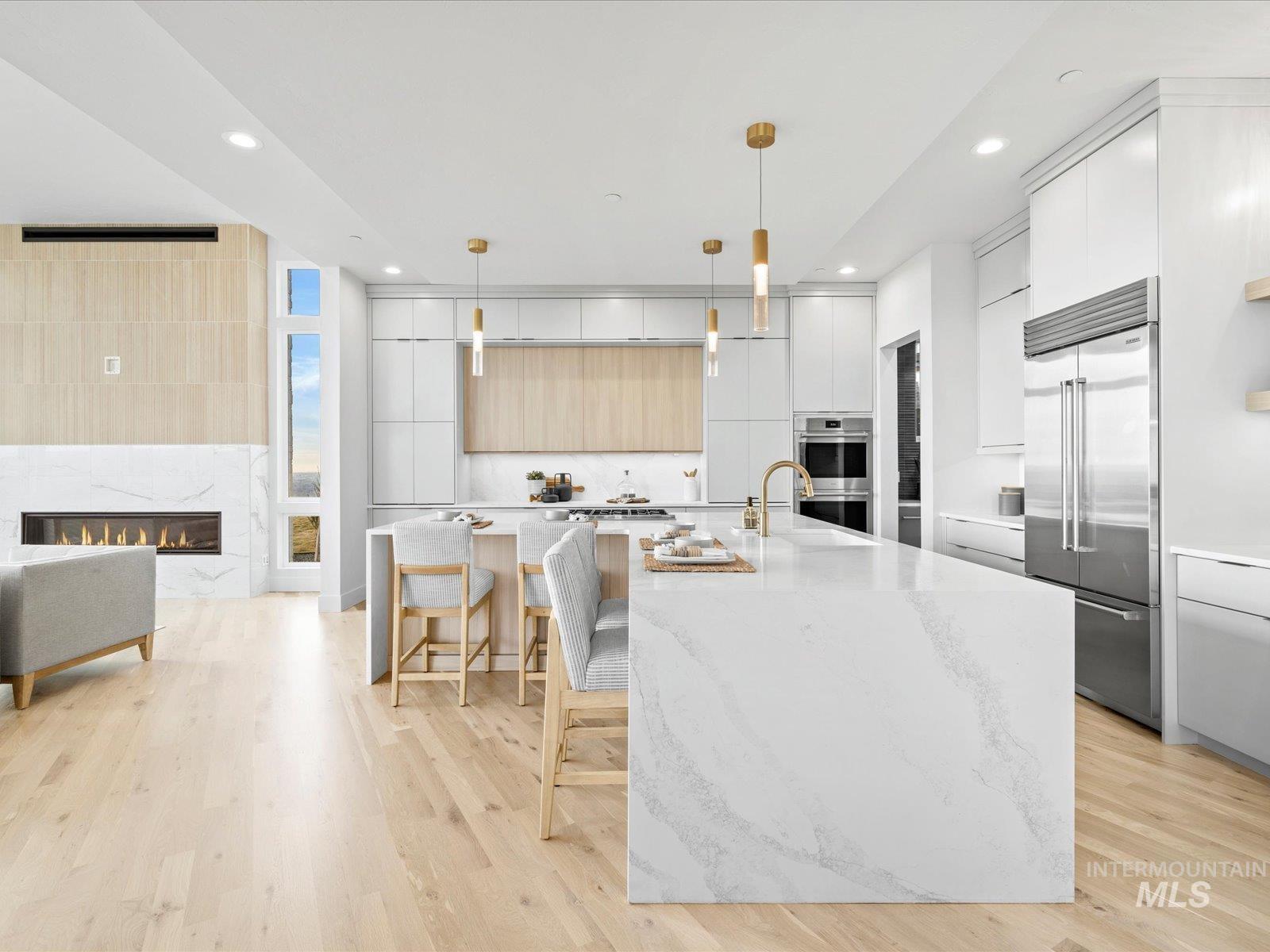 Kitchen featuring modern cabinets, light stone countertops, a premium fireplace, stainless steel appliances, and decorative light fixtures