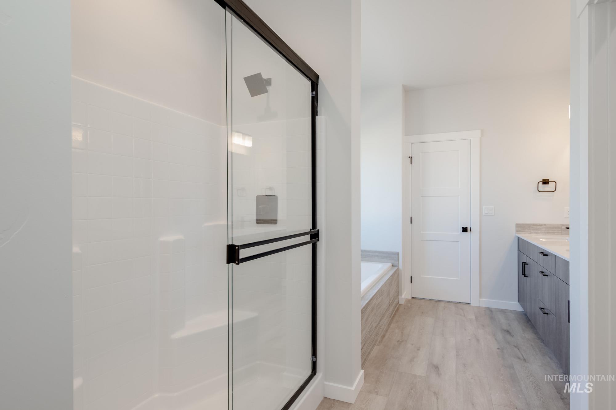 Bathroom with vanity, wood finished floors, a garden tub, and a shower stall