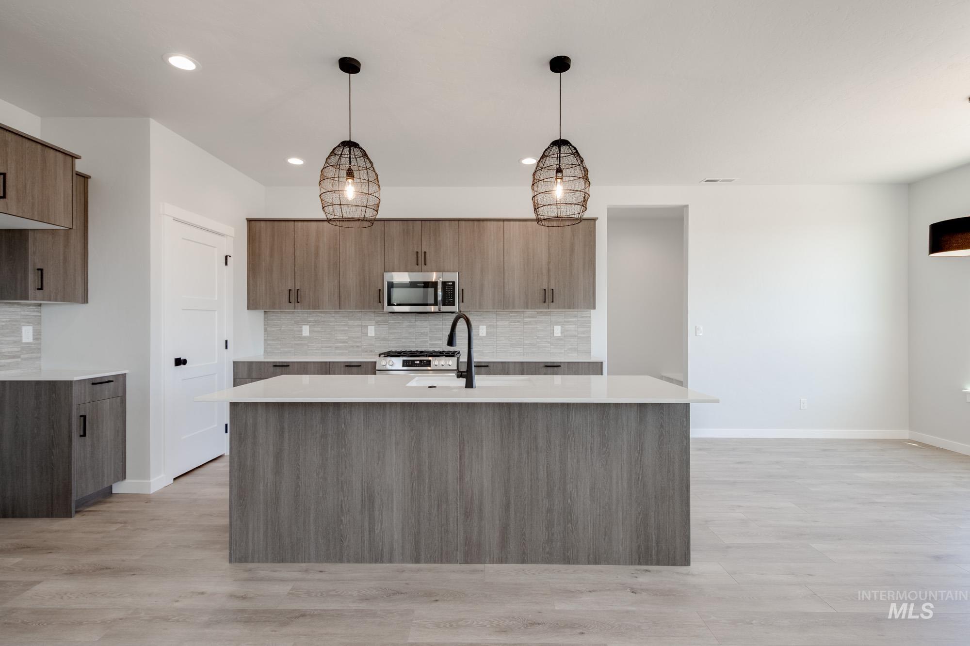 Kitchen with stainless steel microwave, light countertops, backsplash, modern cabinets, and recessed lighting