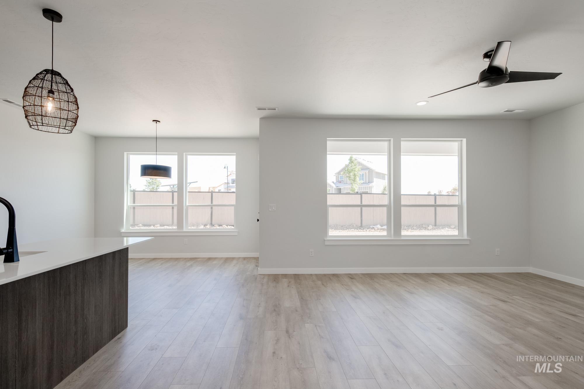 Unfurnished living room featuring plenty of natural light, light wood-type flooring, and a ceiling fan