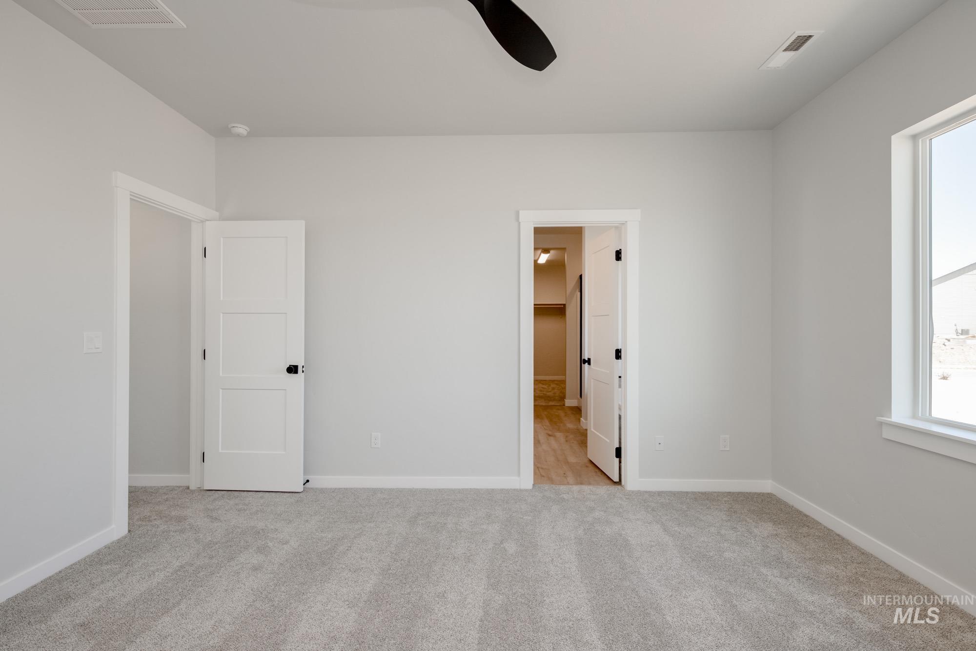 Unfurnished bedroom featuring carpet, ceiling fan, and connected bathroom