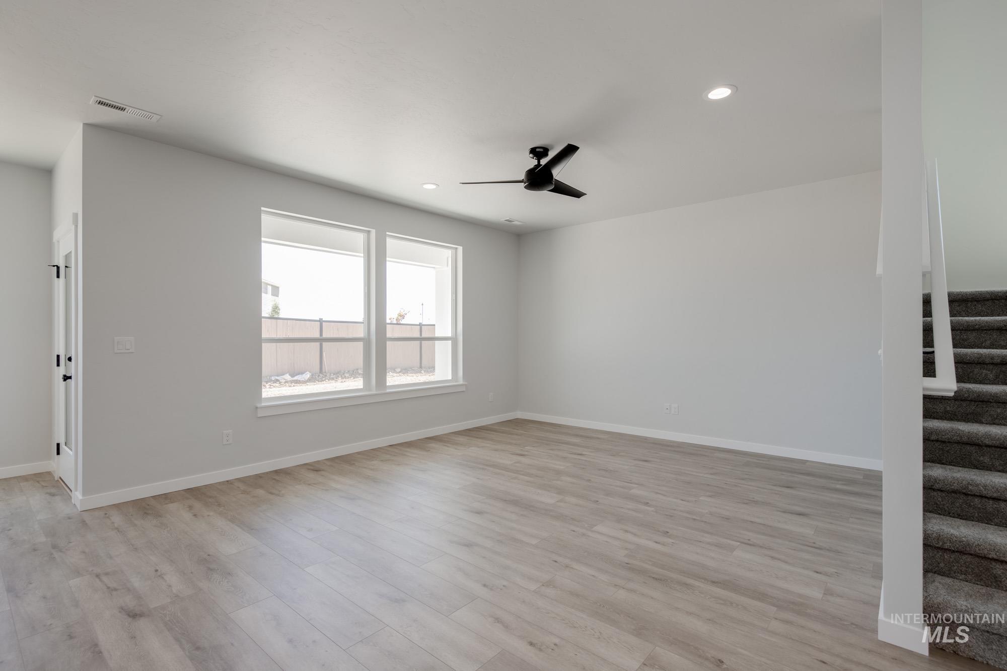 Unfurnished living room featuring stairway, a ceiling fan, recessed lighting, and light wood finished floors