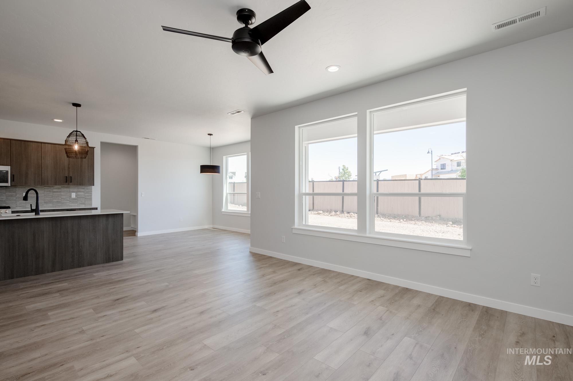 Unfurnished living room featuring light wood-style floors, a ceiling fan, and recessed lighting