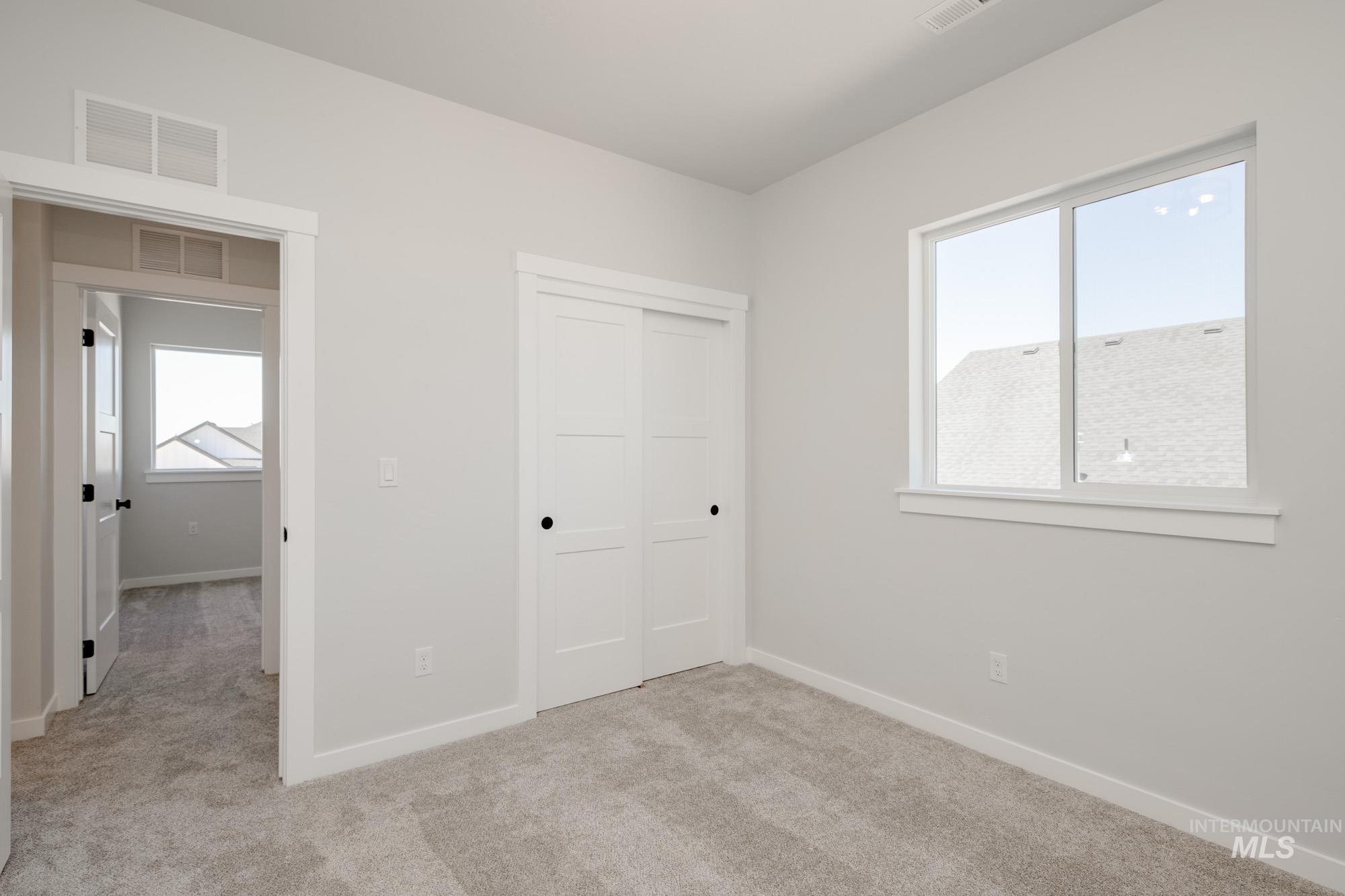 Unfurnished bedroom featuring light carpet and a closet