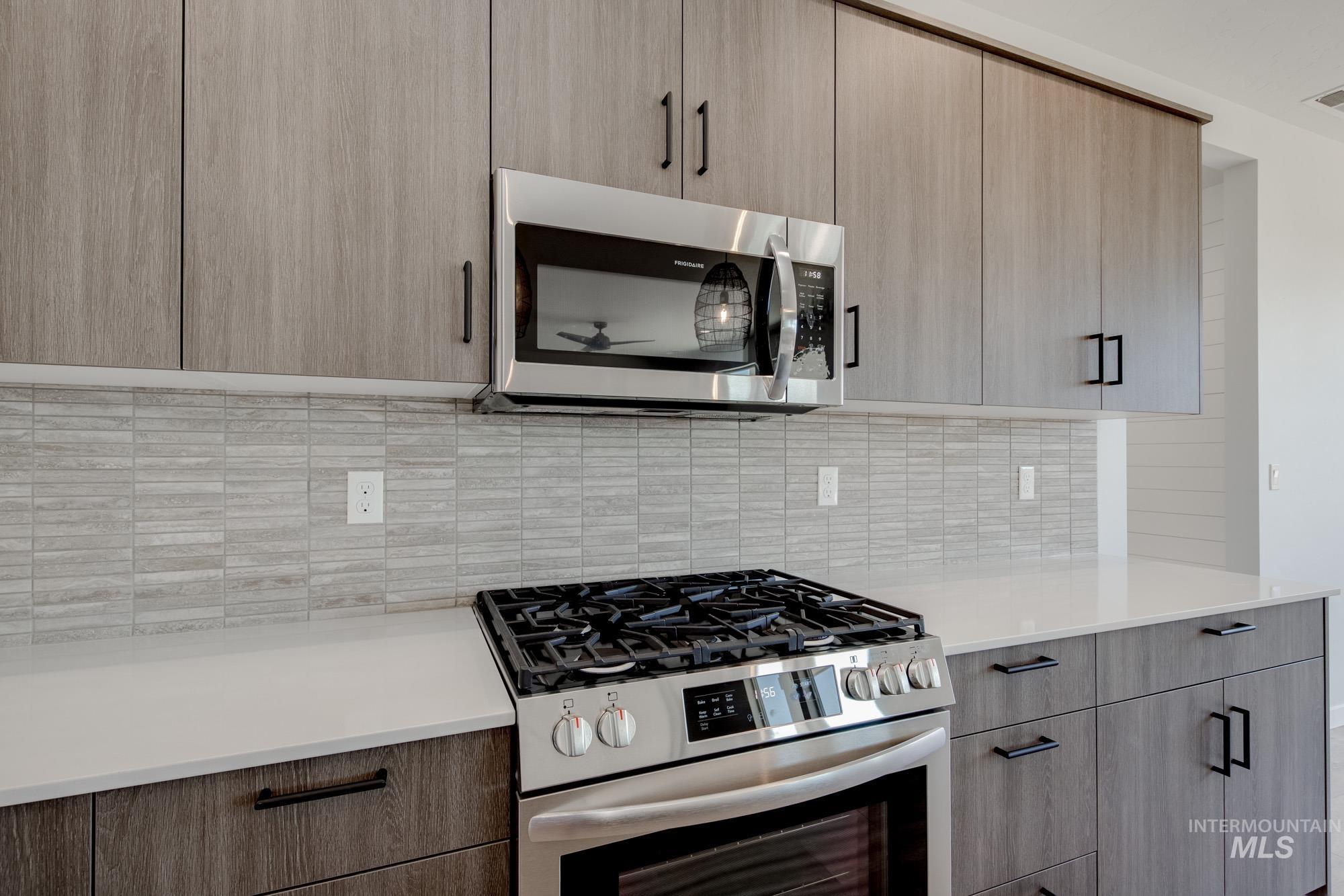 Kitchen featuring appliances with stainless steel finishes, decorative backsplash, light countertops, and modern cabinets