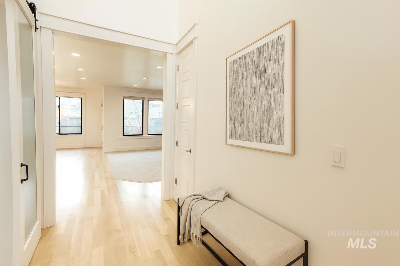 Hallway with light wood finished floors, recessed lighting, and a barn door