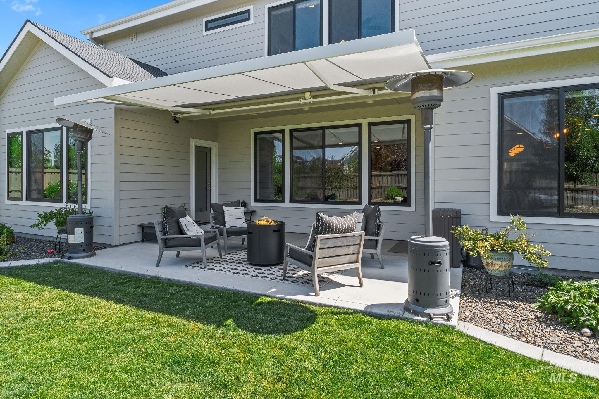 Back of house with an outdoor fire pit, a patio, and a lawn