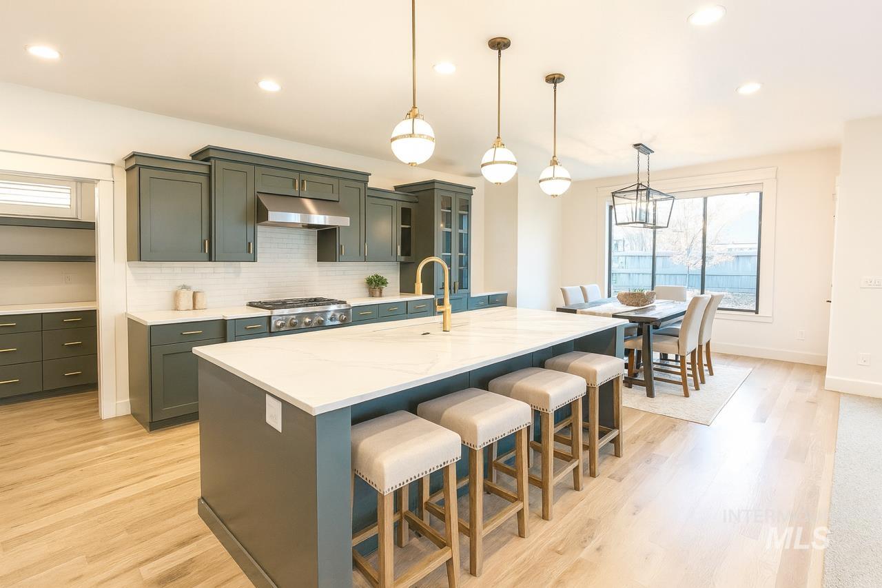 Kitchen with tasteful backsplash, recessed lighting, decorative light fixtures, a kitchen island with sink, and light wood-type flooring