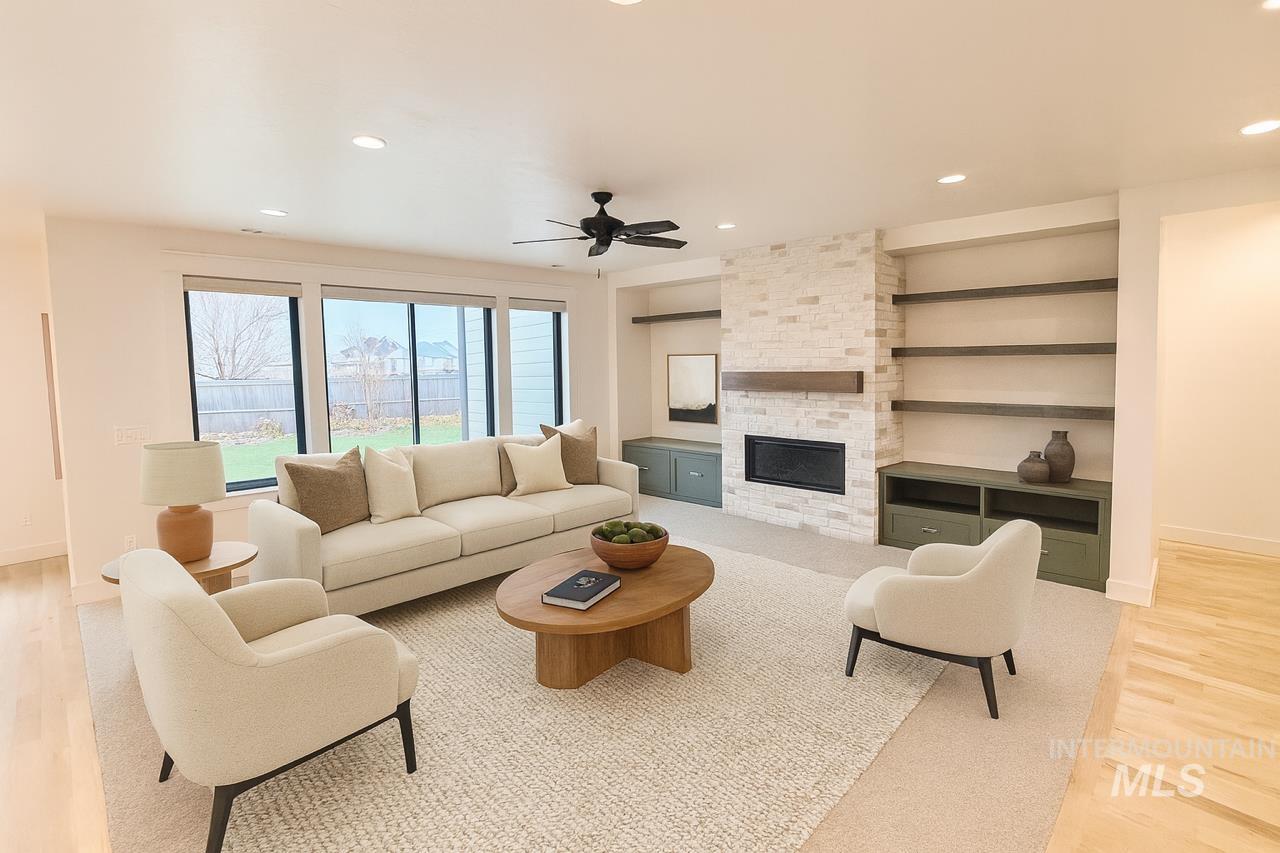 Living room featuring light wood-type flooring, recessed lighting, a stone fireplace, ceiling fan, and built in features