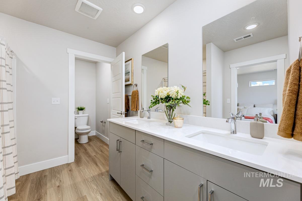Bathroom featuring double vanity, light wood-style floors, a shower with shower curtain, and recessed lighting