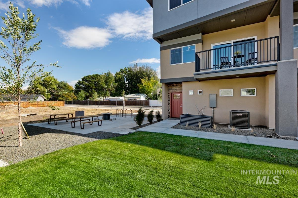 Rear view of property featuring stucco siding, a balcony, a patio, and stone siding