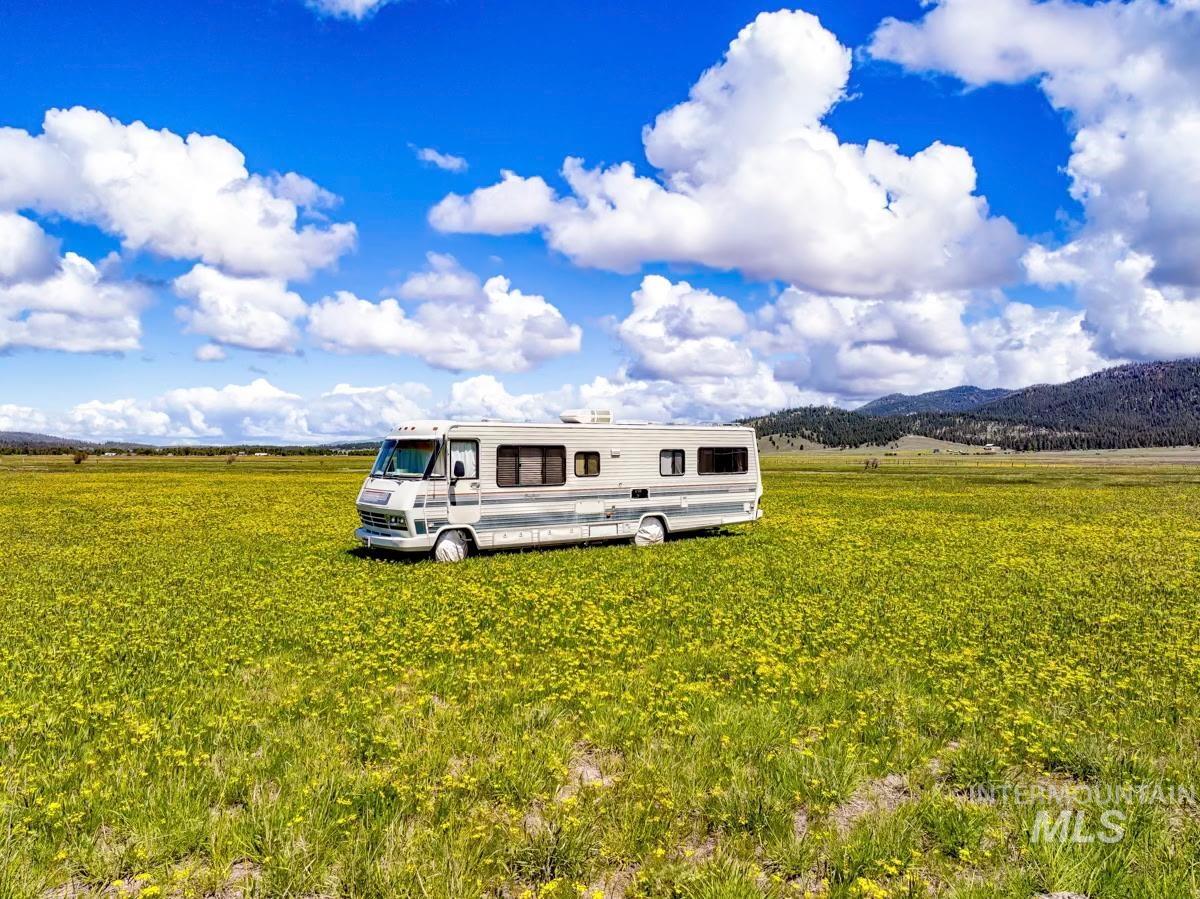 Rear view of property featuring a mountain view, a view of countryside, and a yard