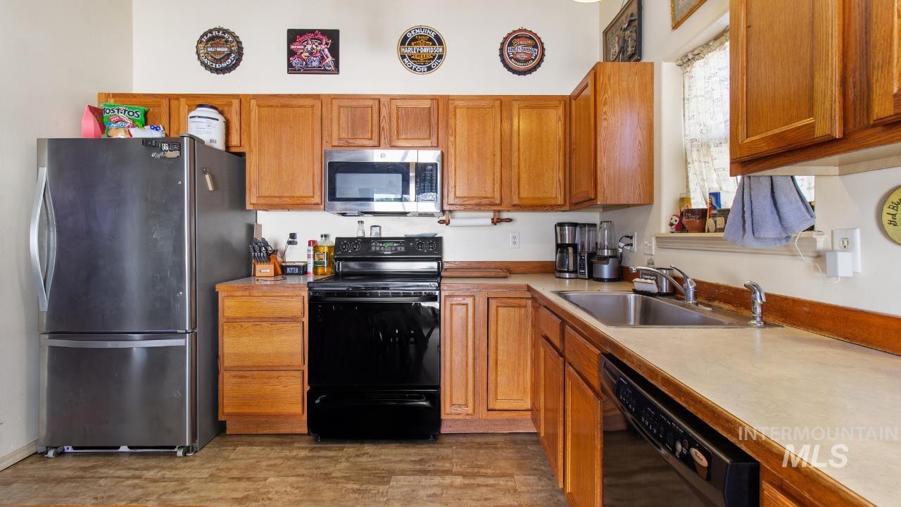 Kitchen featuring black appliances, brown cabinetry, light countertops, and light wood-style floors
