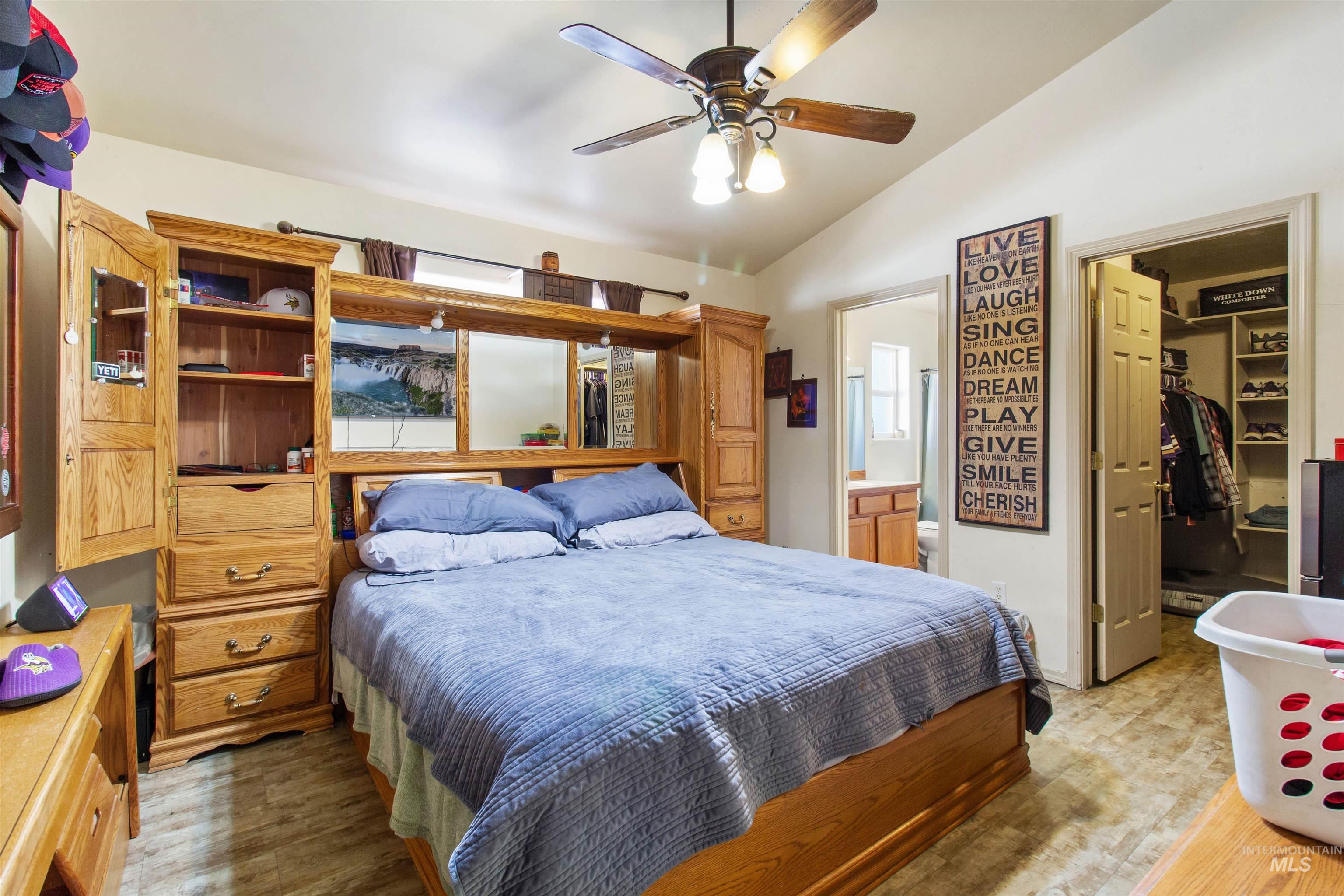 Bedroom with a walk in closet, lofted ceiling, ceiling fan, and connected bathroom