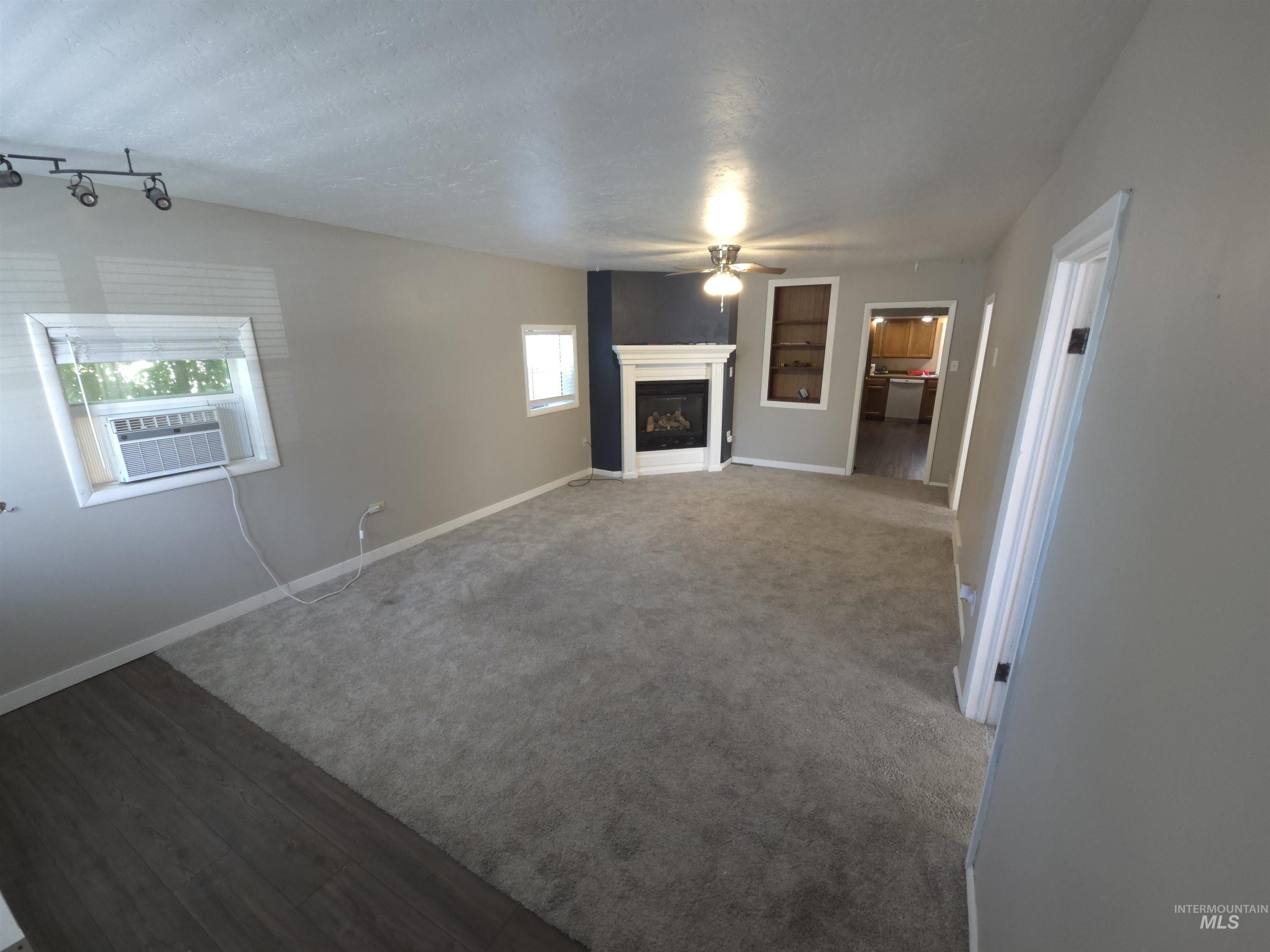 Unfurnished living room with ceiling fan, a fireplace, carpet, and wood finished floors