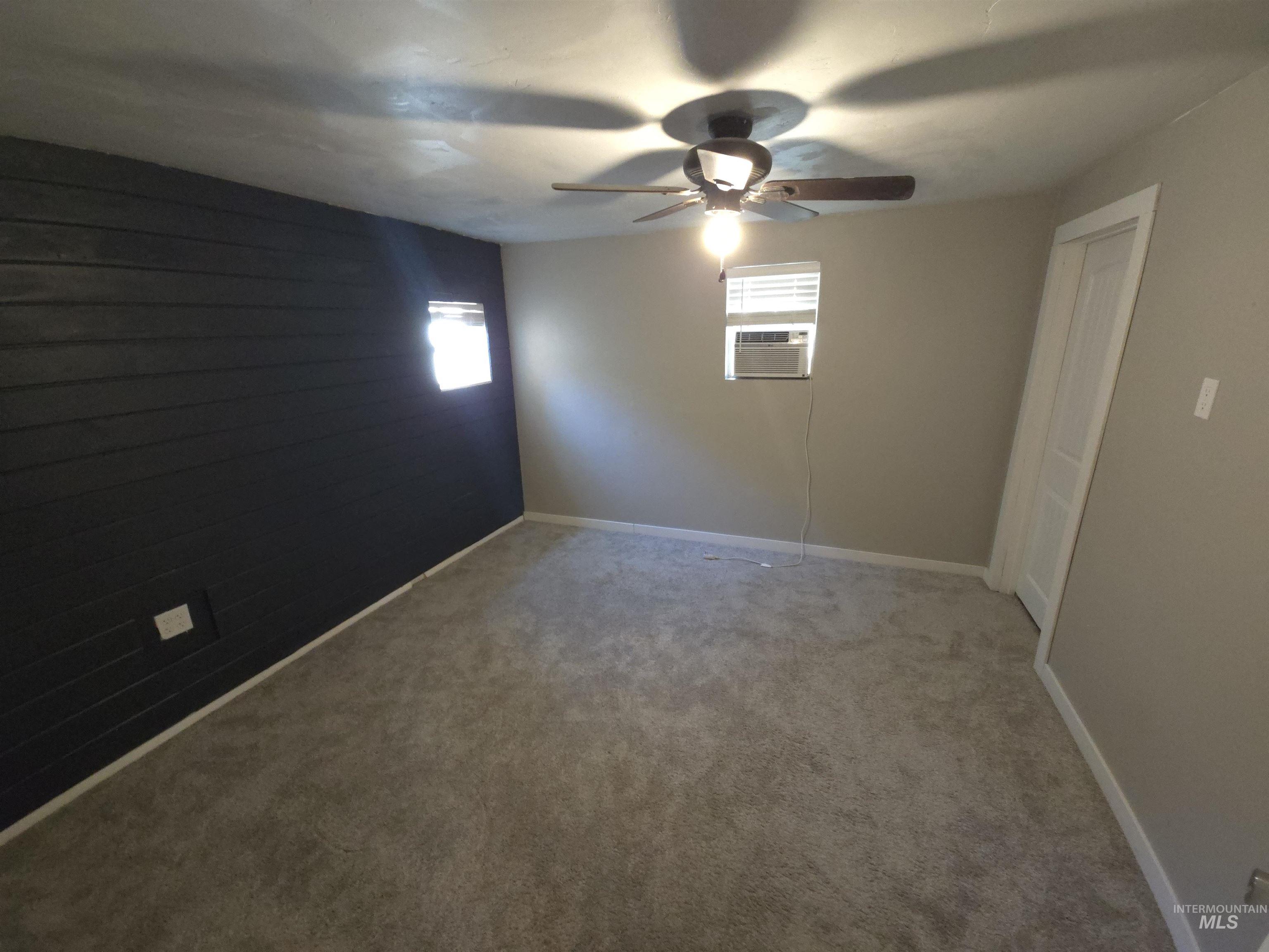 Carpeted spare room featuring ceiling fan and baseboards