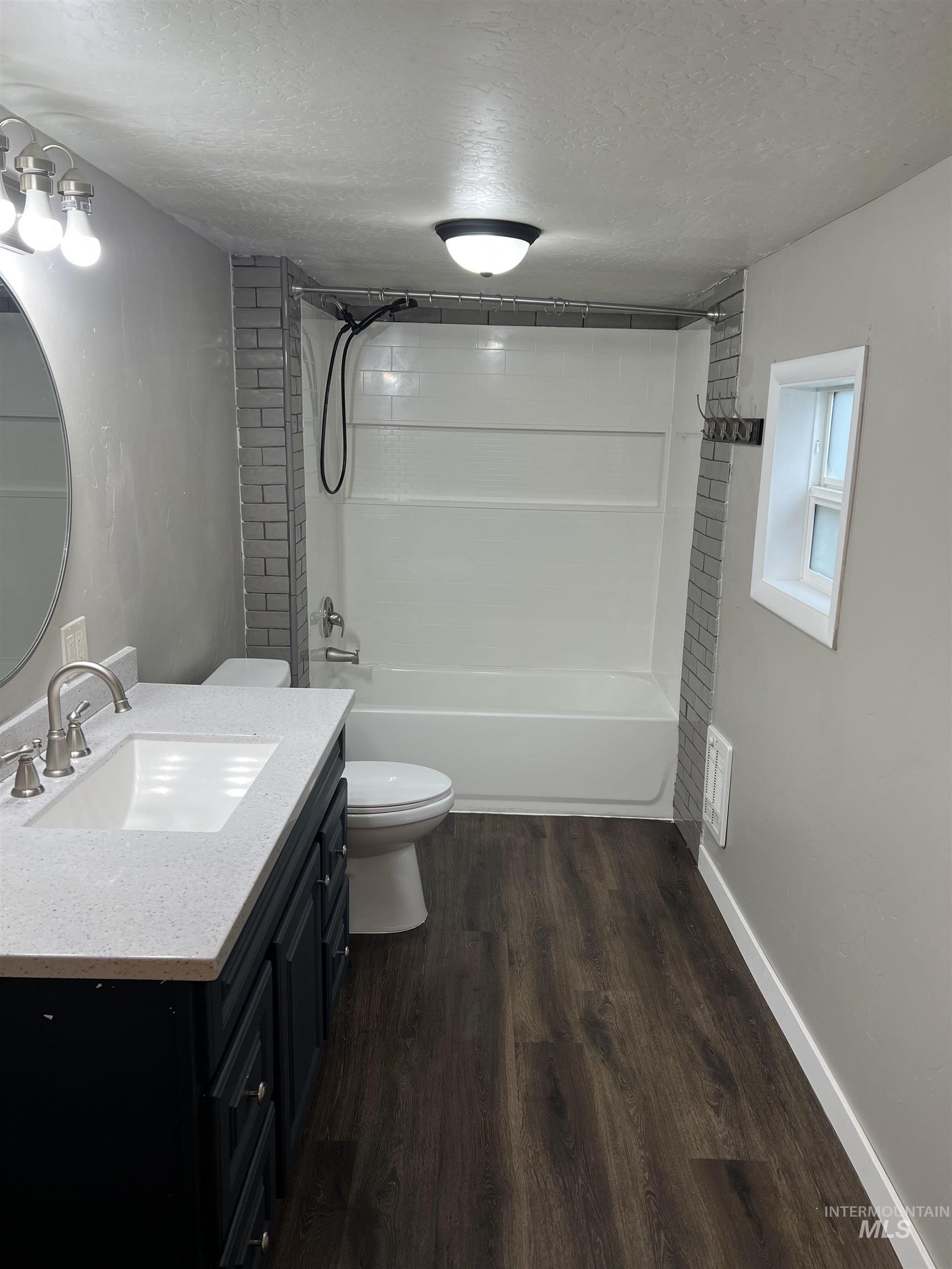 Full bathroom featuring a textured ceiling, vanity, wood finished floors, and shower / washtub combination