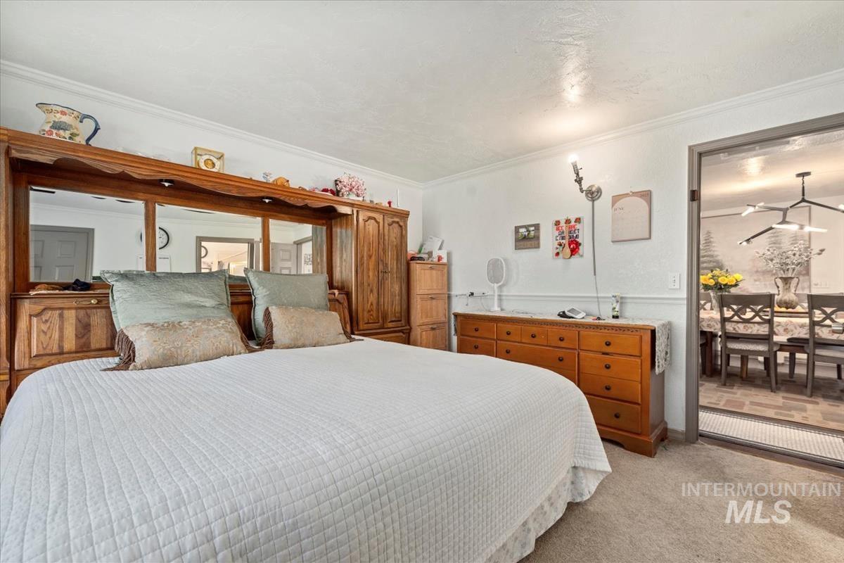 Bedroom with ornamental molding and light carpet