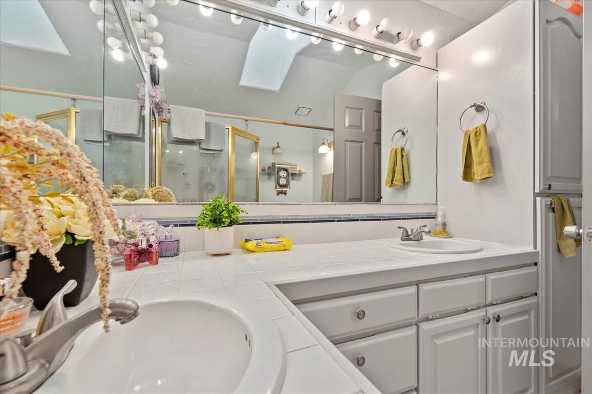 Full bath with a skylight, double vanity, and a stall shower