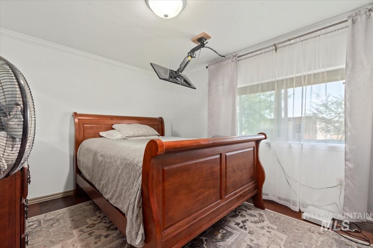 Bedroom featuring light wood finished floors and crown molding