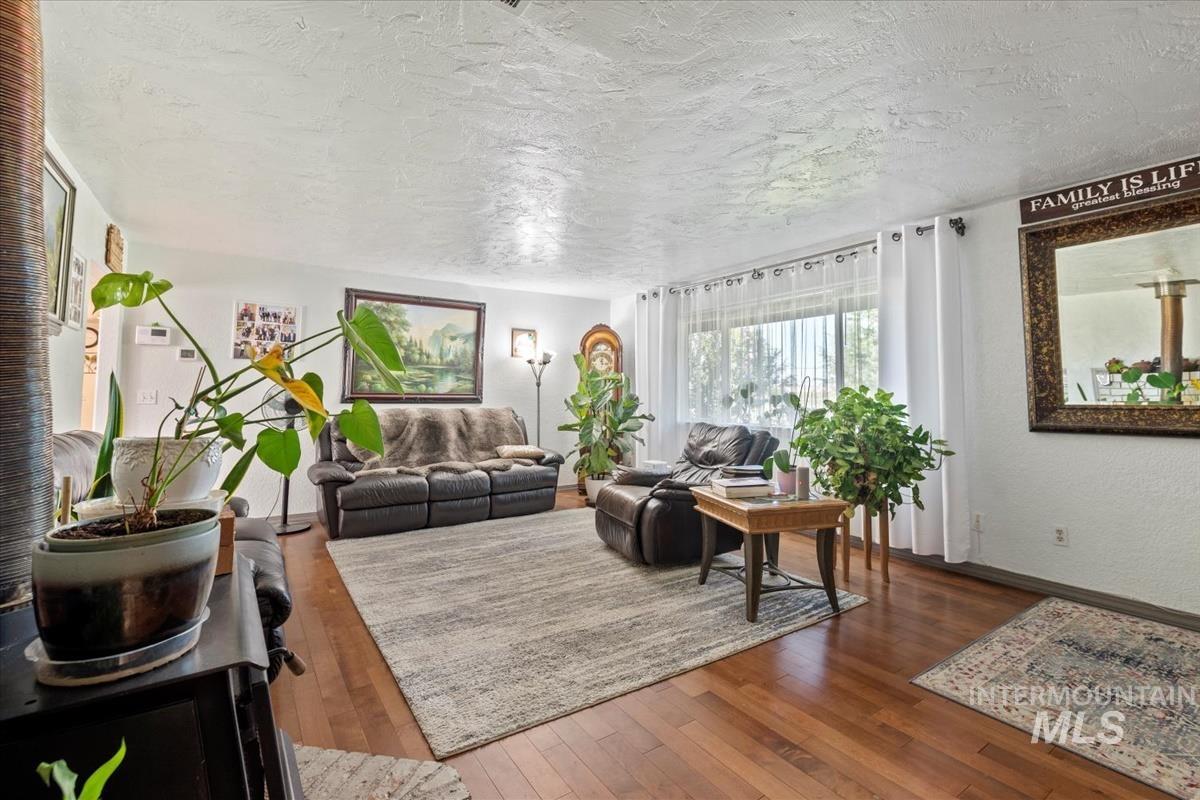 Living area featuring hardwood / wood-style floors, a textured ceiling, and a textured wall