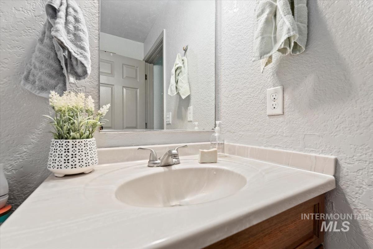 Bathroom featuring a textured wall and vanity