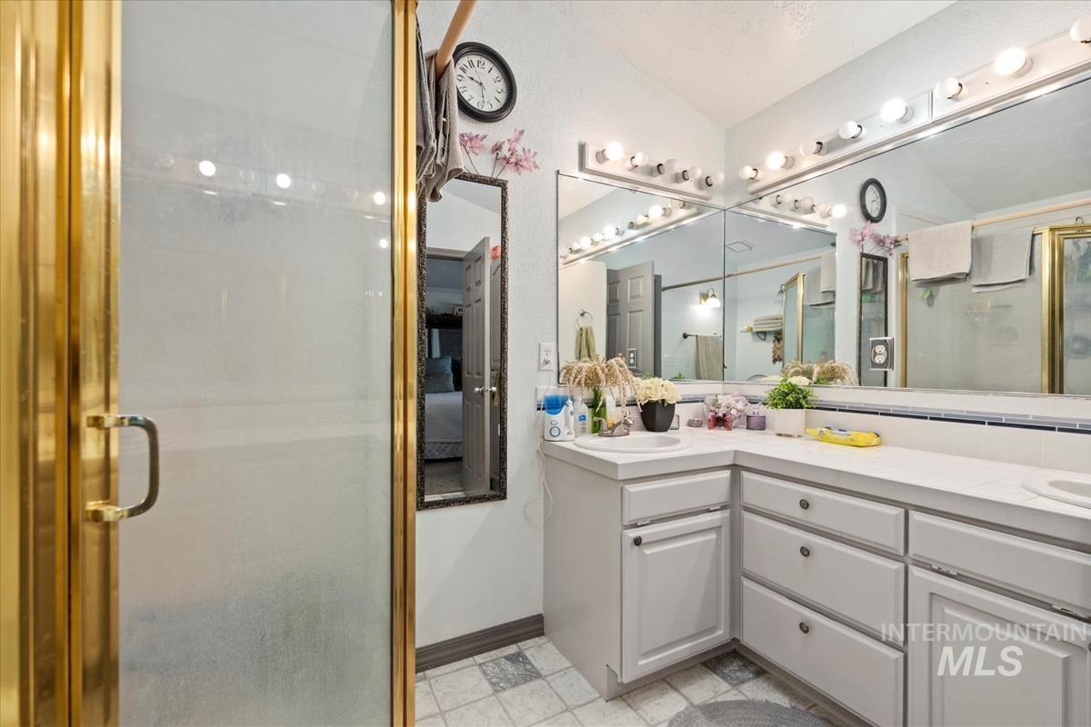 Bathroom featuring a stall shower and double vanity