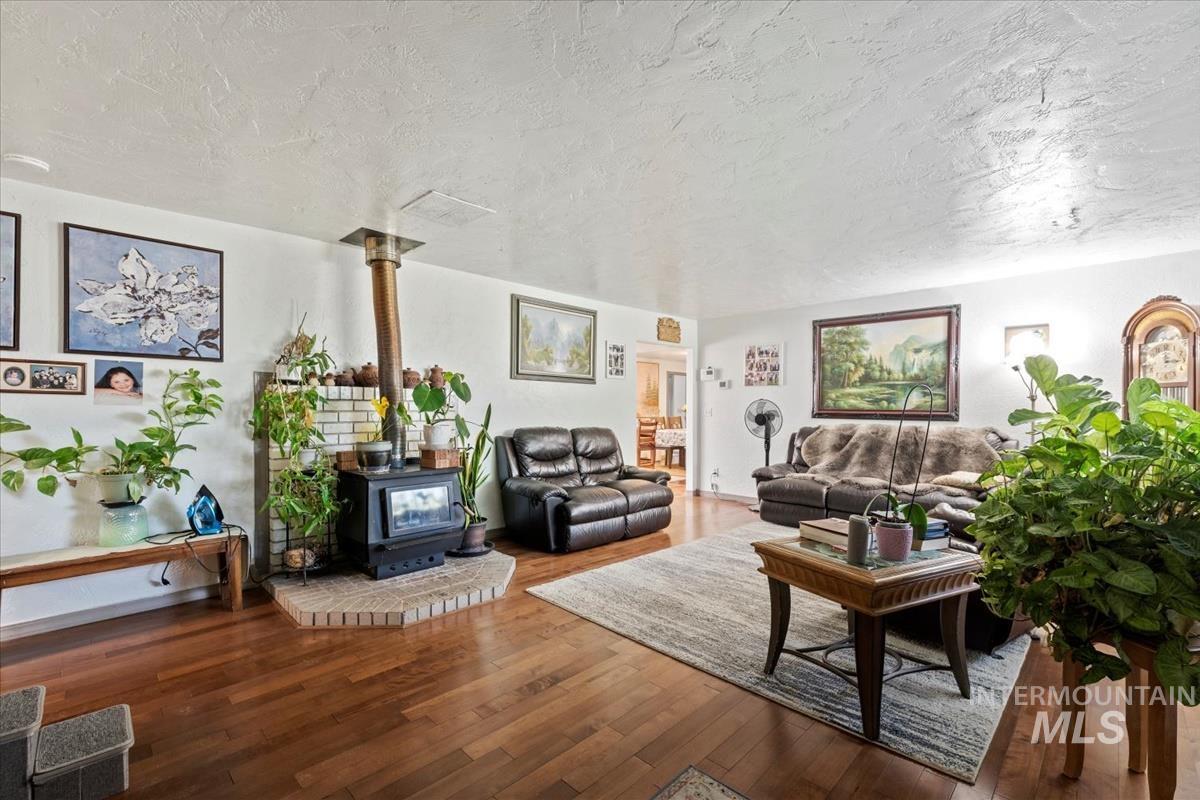 Living room featuring a wood stove, a textured ceiling, and hardwood / wood-style flooring