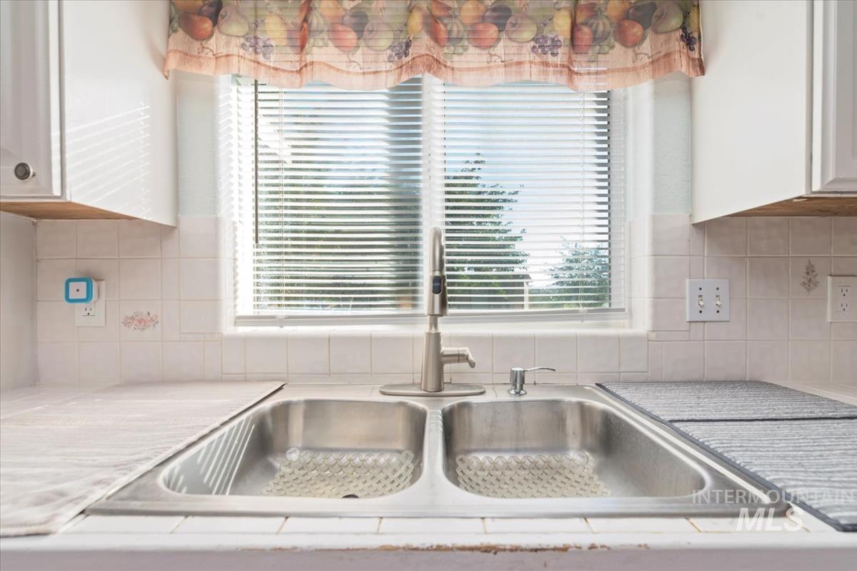 Kitchen view of decorative backsplash and white cabinets