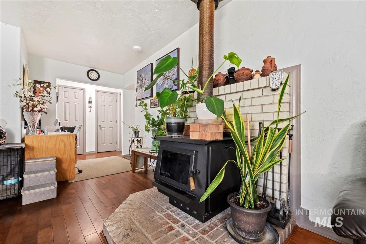 Sitting room featuring dark wood-type flooring, a wood stove, and stairway