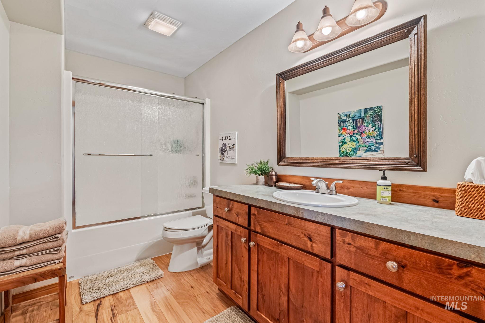 Bathroom with vanity, combined bath / shower with glass door, and light wood finished floors