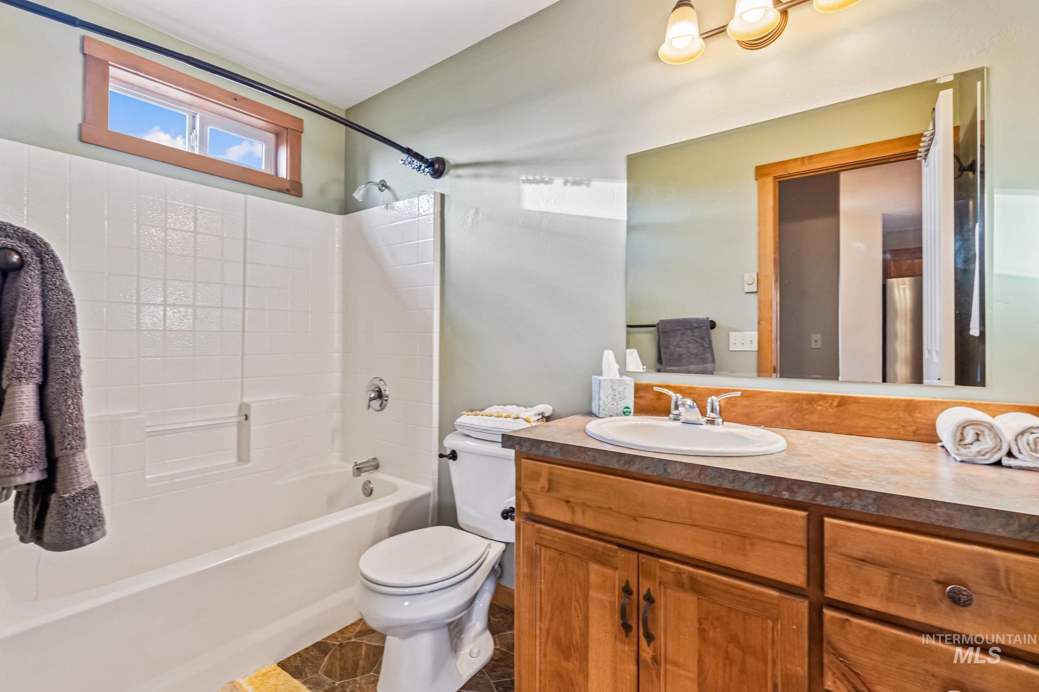 Bathroom with shower / bath combination, vanity, and dark tile patterned flooring
