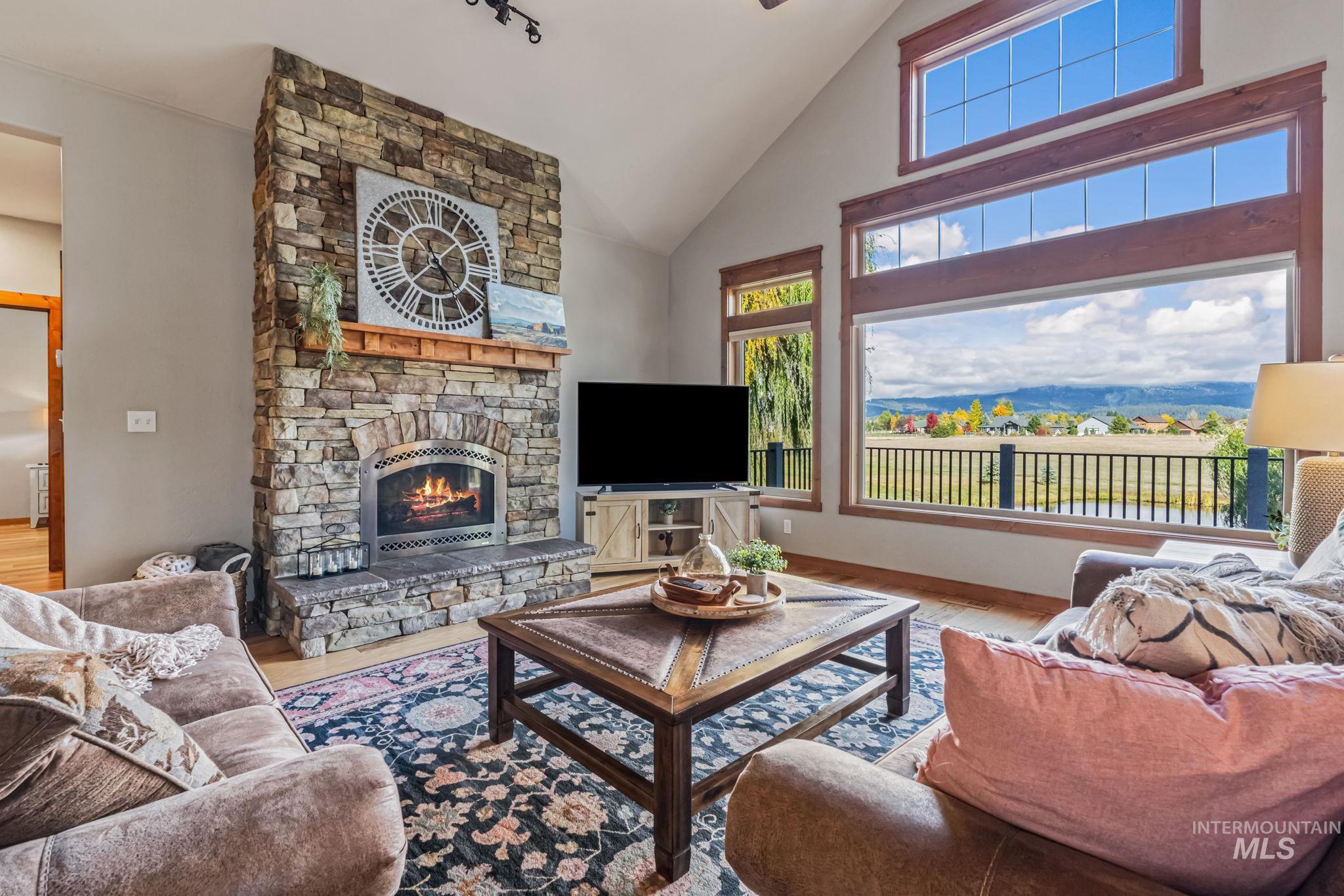 Living room featuring a fireplace, high vaulted ceiling, and wood finished floors