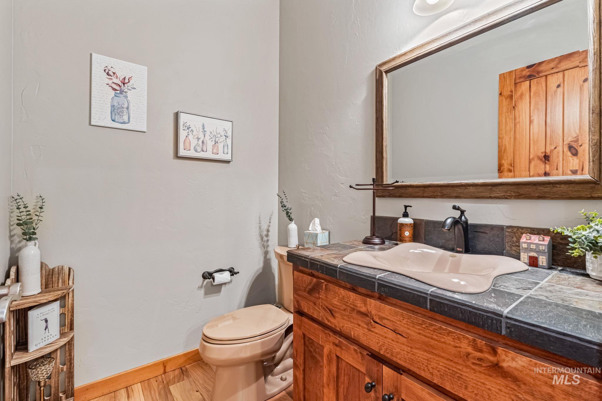 Half bath with a textured wall, vanity, and wood finished floors