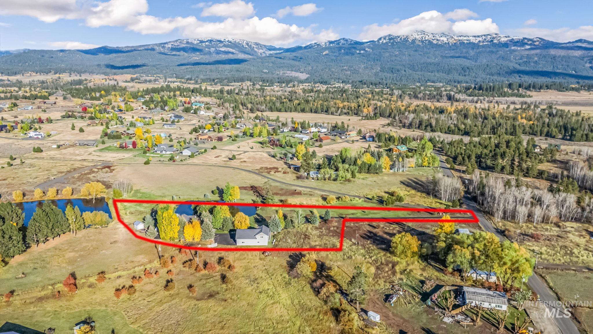 Aerial view of property and surrounding area with mountains and property parcel outlined